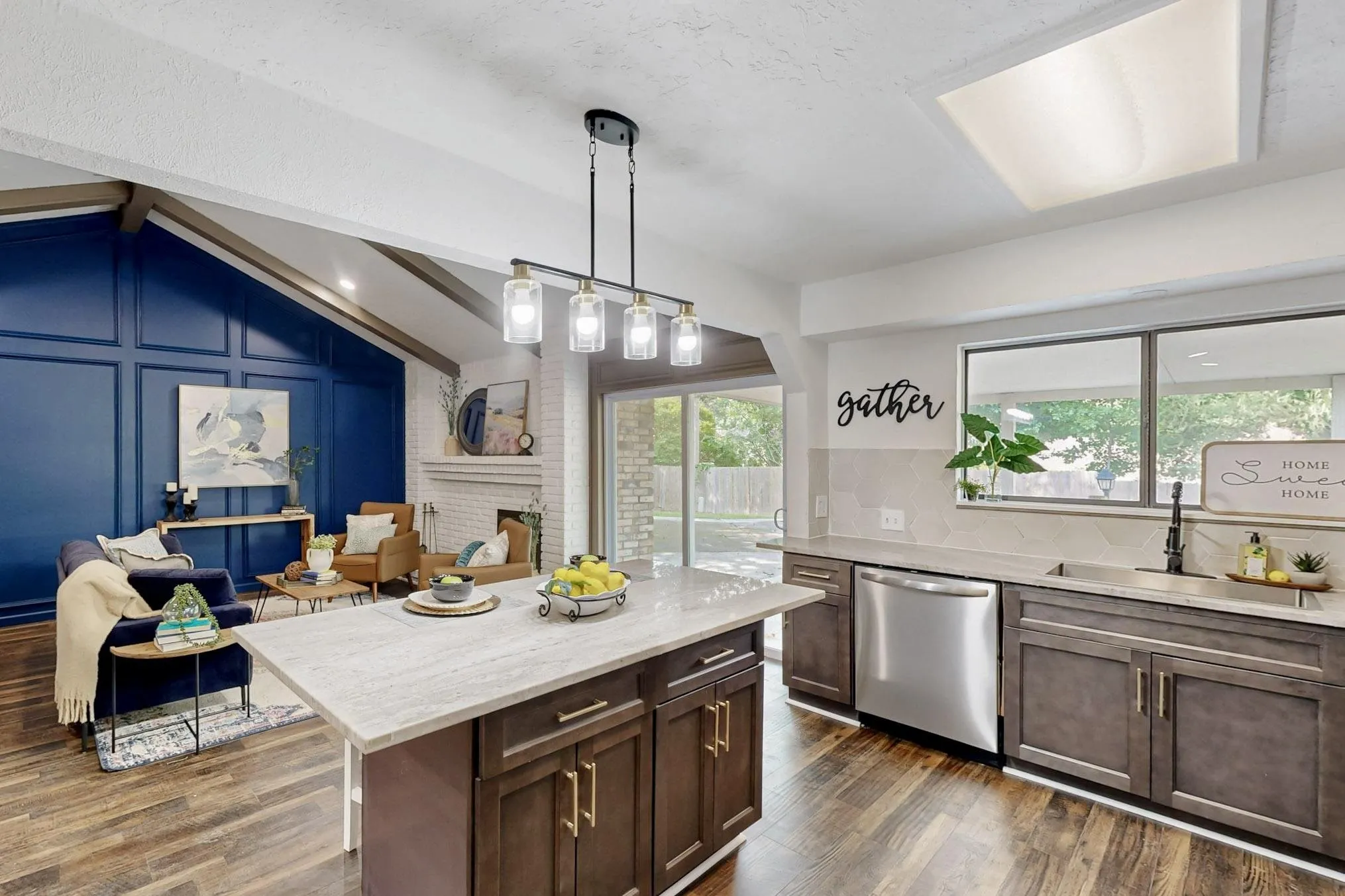 Open-concept living space featuring wood-finish flooring, a kitchen island with a light-toned countertop, and dark wood cabinetry