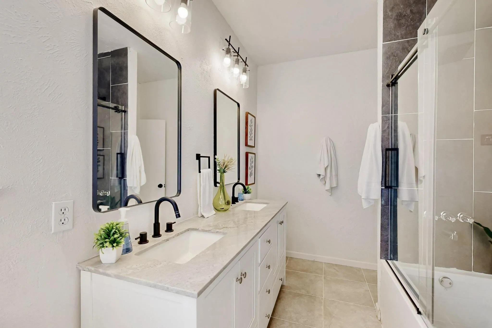 Dual vanity with white cabinetry, light-toned countertop, and matte black fixtures