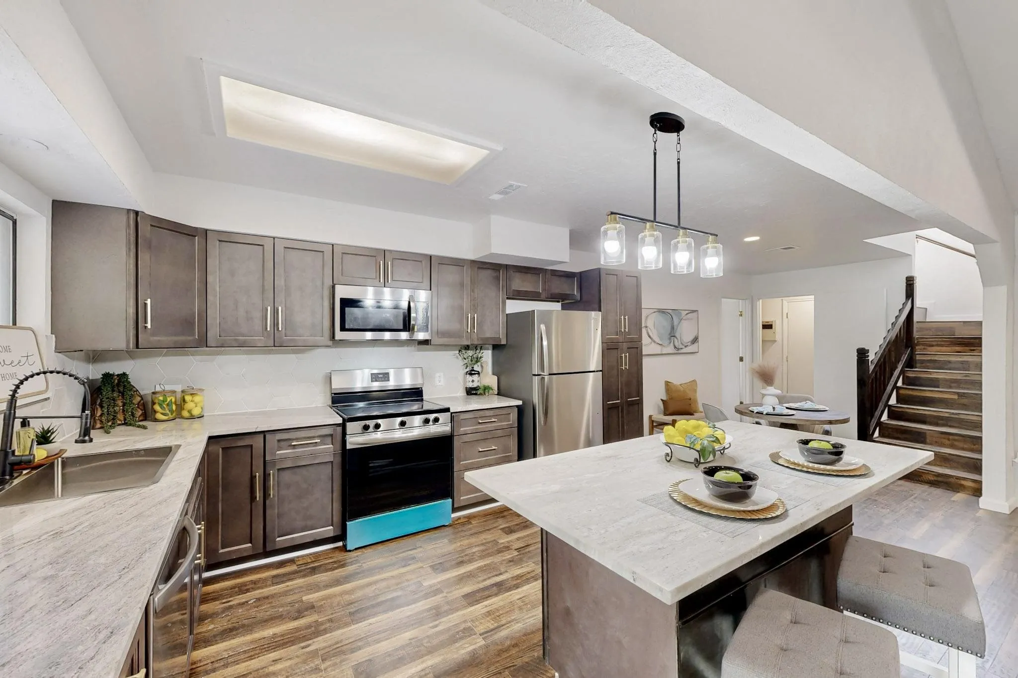 Modern kitchen with wood-finish flooring, light-toned countertops, and dark cabinetry