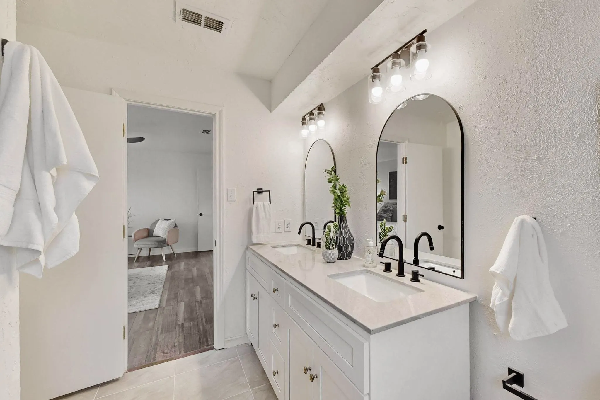 Double vanity featuring white shaker cabinetry, light-toned countertops, and matte black fixtures