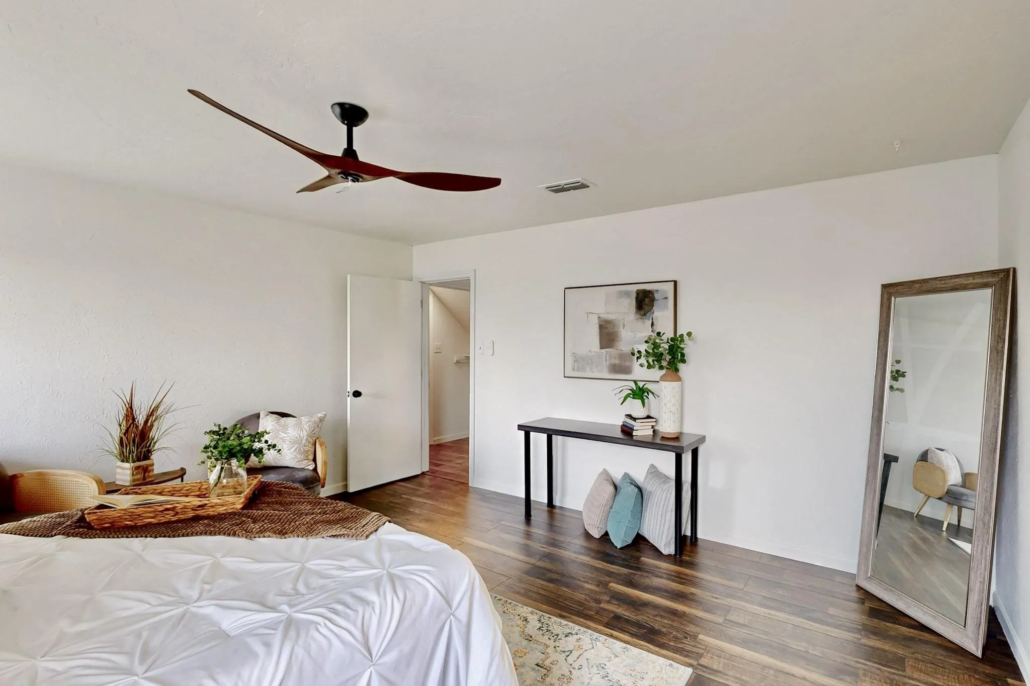 Spacious room featuring wood-finish flooring, a modern ceiling fan, and white walls