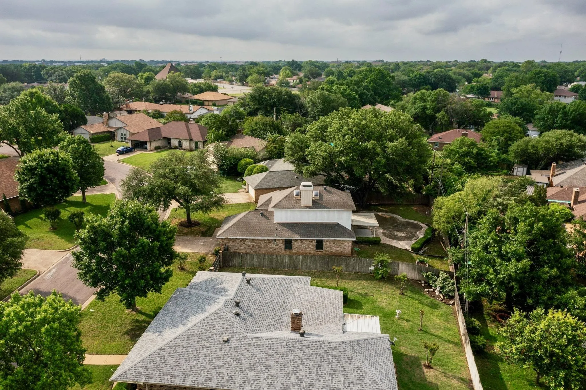 Aerial perspective showcasing a residential property with a shingled roof and multiple chimneys