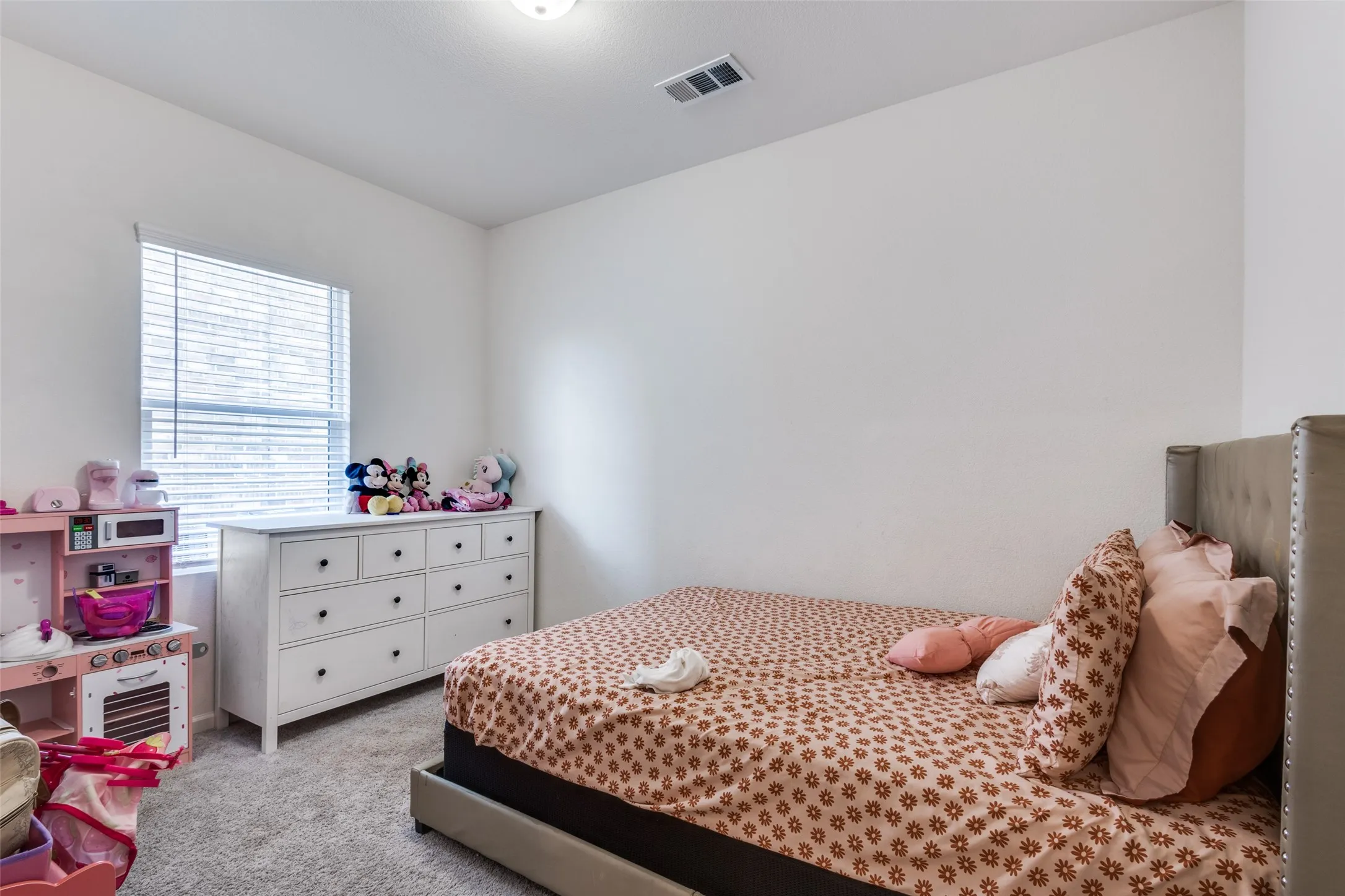 Carpeted room featuring a single window with blinds, white walls, and a ceiling light fixture