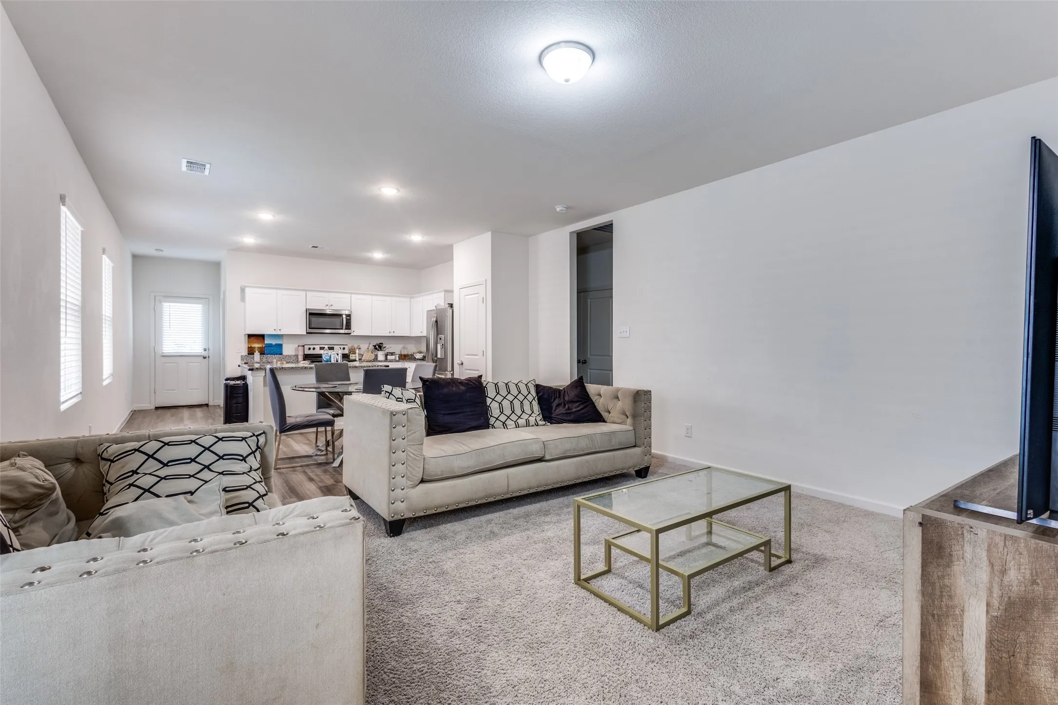 Open-concept living space featuring light carpeting and neutral wall tones