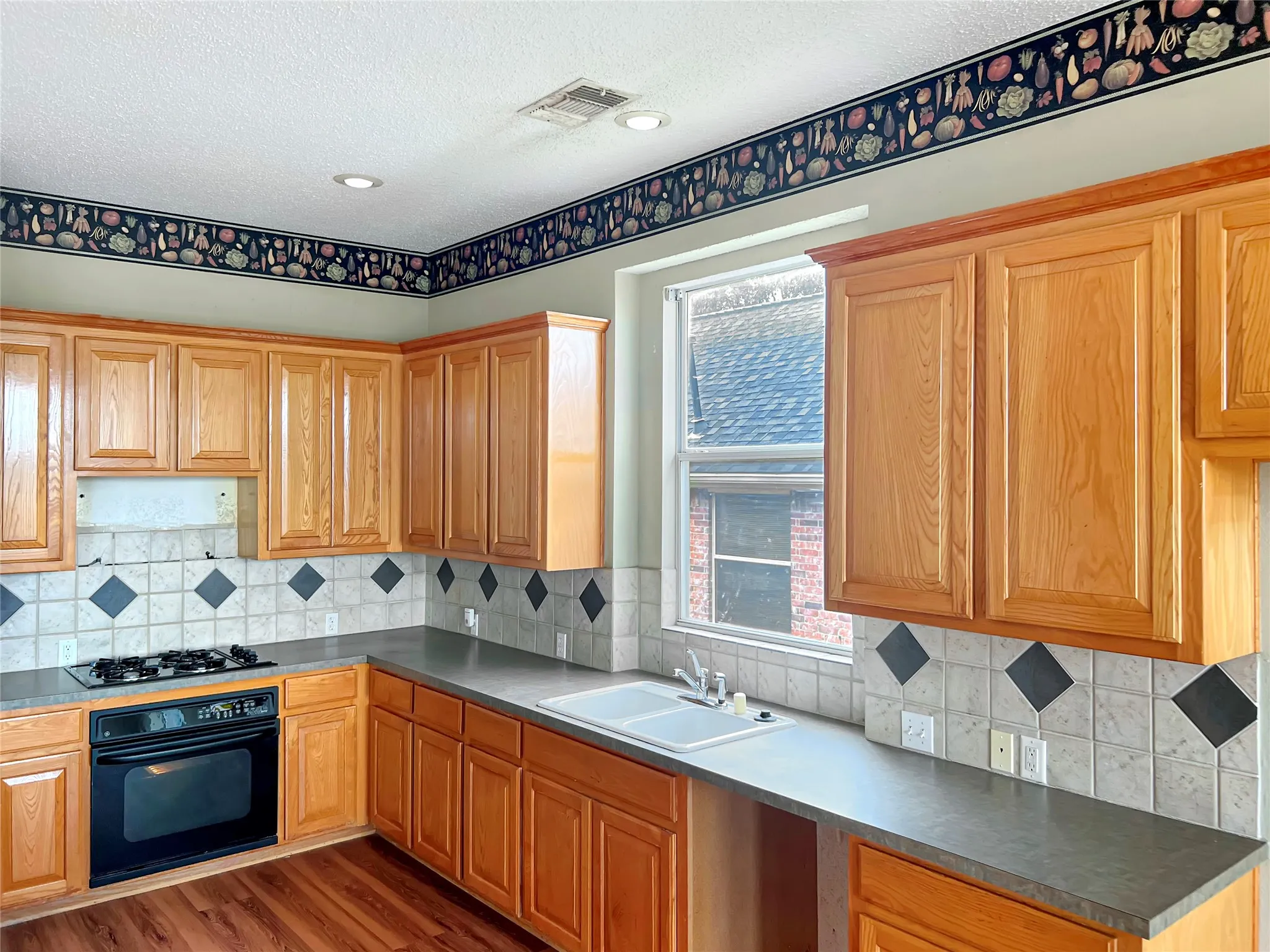 Kitchen featuring wood-finish cabinetry, dark countertops, and a white double-basin sink