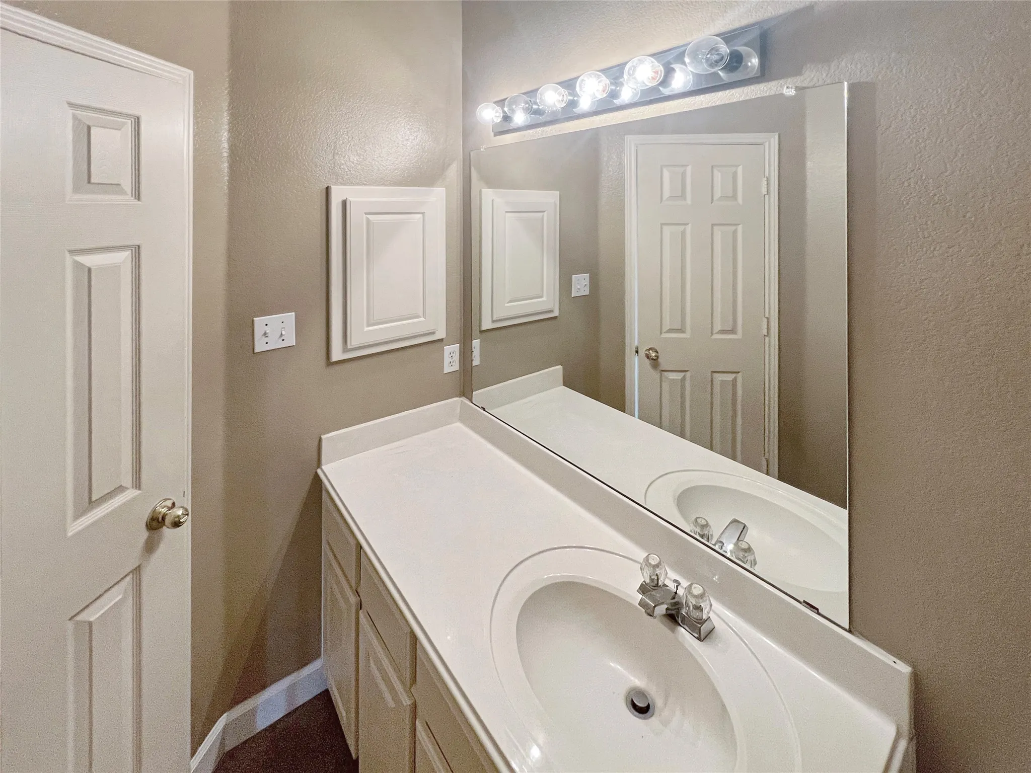 Bathroom vanity featuring a single integrated sink, white countertop, and white cabinetry