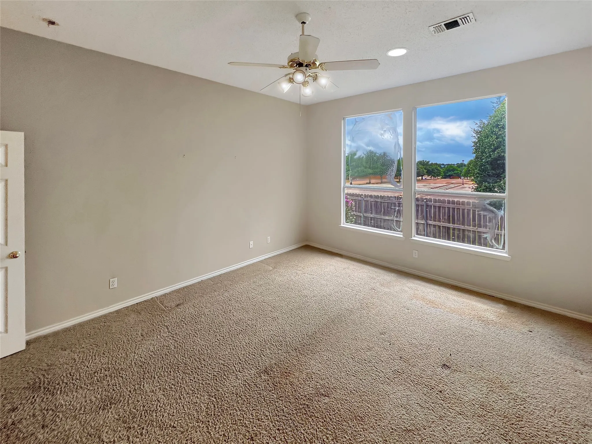 Room featuring two large windows, carpet flooring, a ceiling fan with integrated lighting, and recessed ceiling lighting