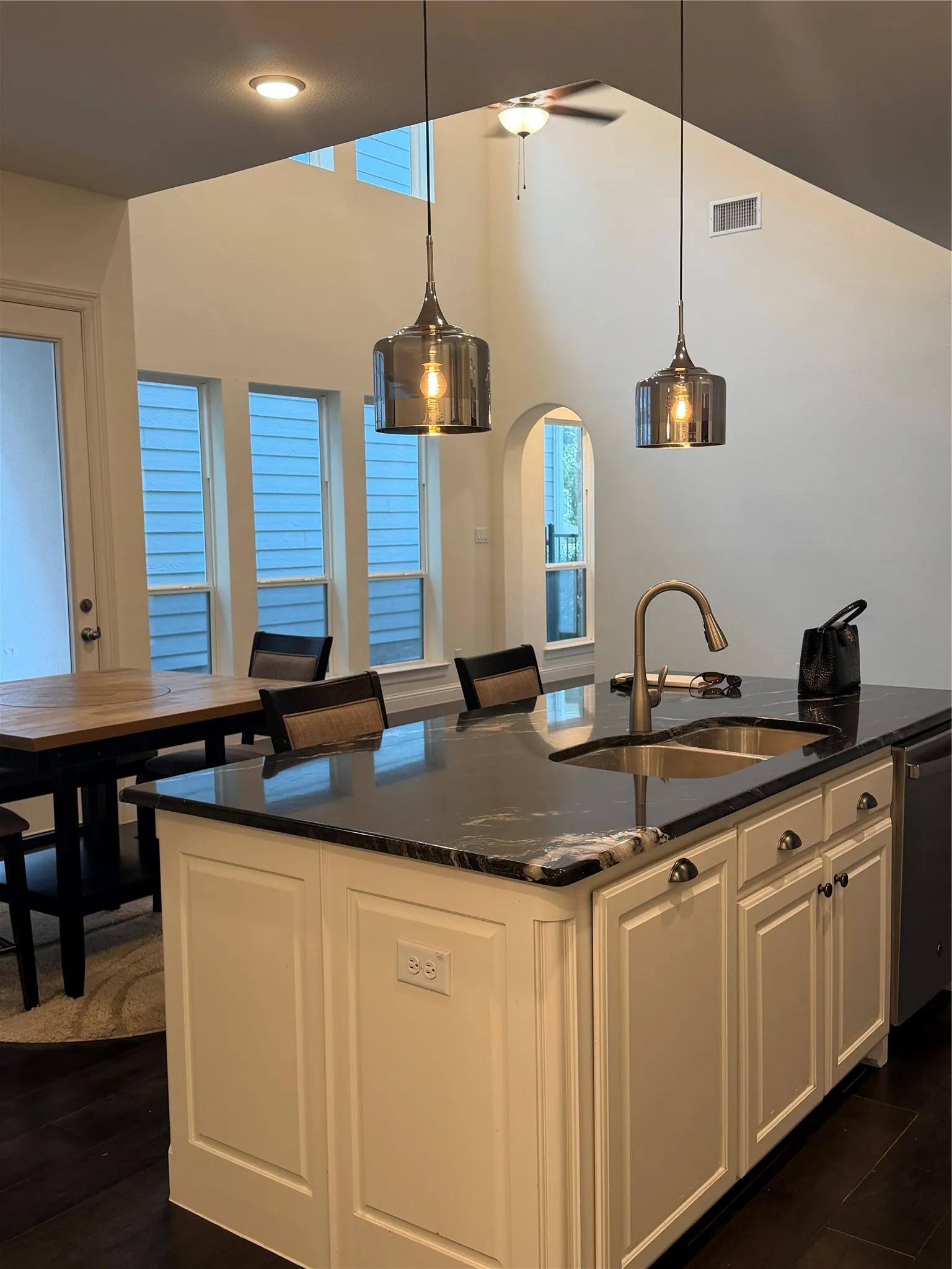 Kitchen island with dark countertop, undermount sink, and gooseneck faucet