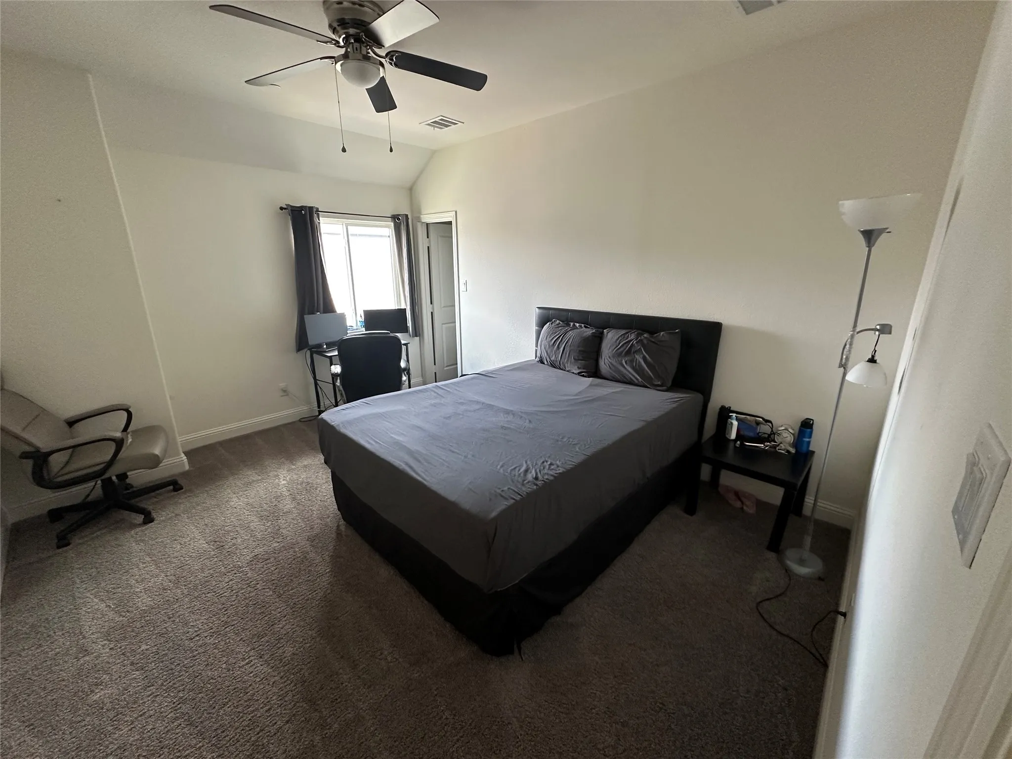 Carpeted room featuring a ceiling fan with integrated lighting, a window with dark draperies, and a built-in closet with a white panel door