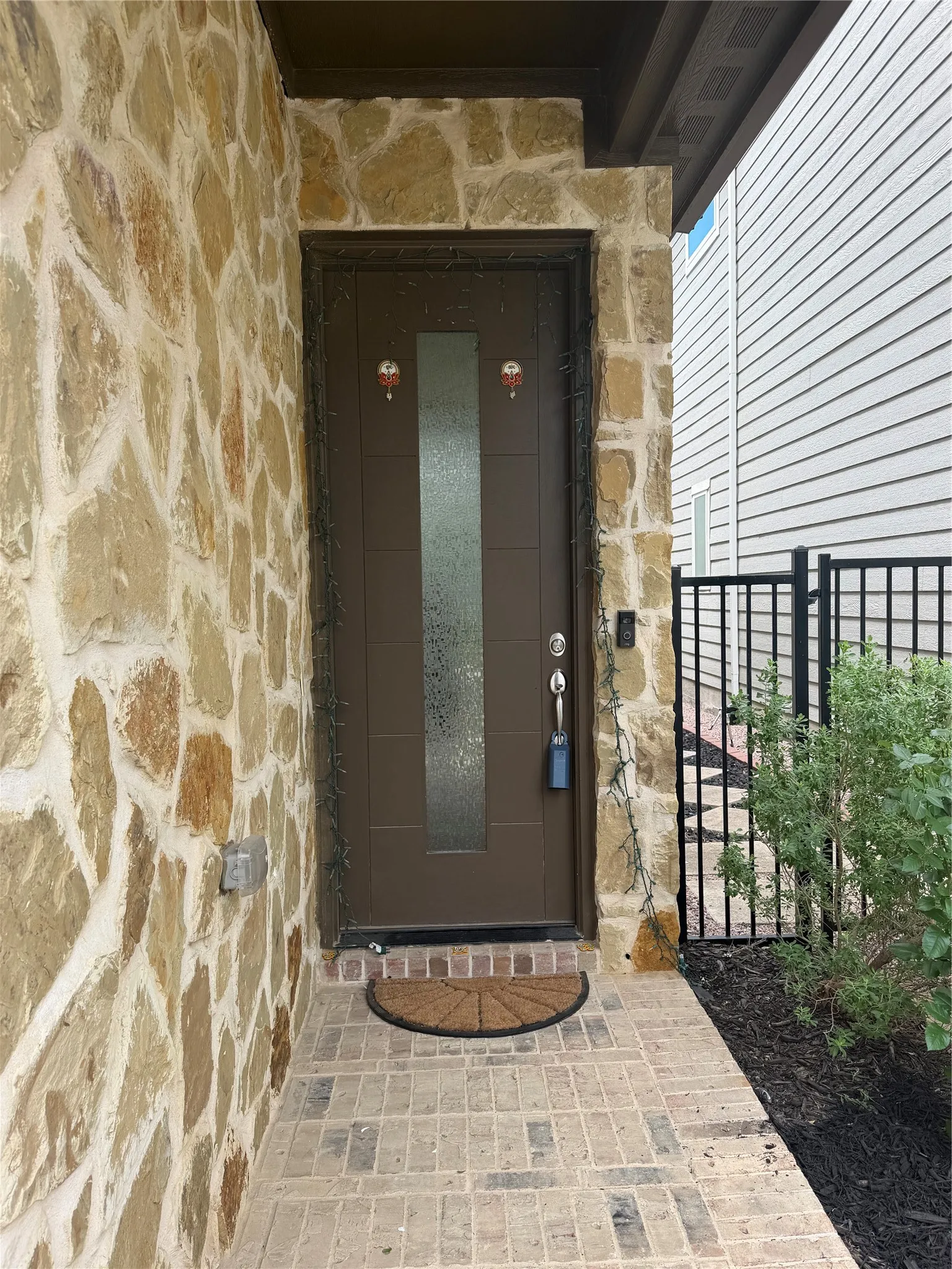 Entryway featuring a brown door with a frosted glass insert, framed by natural stone siding
