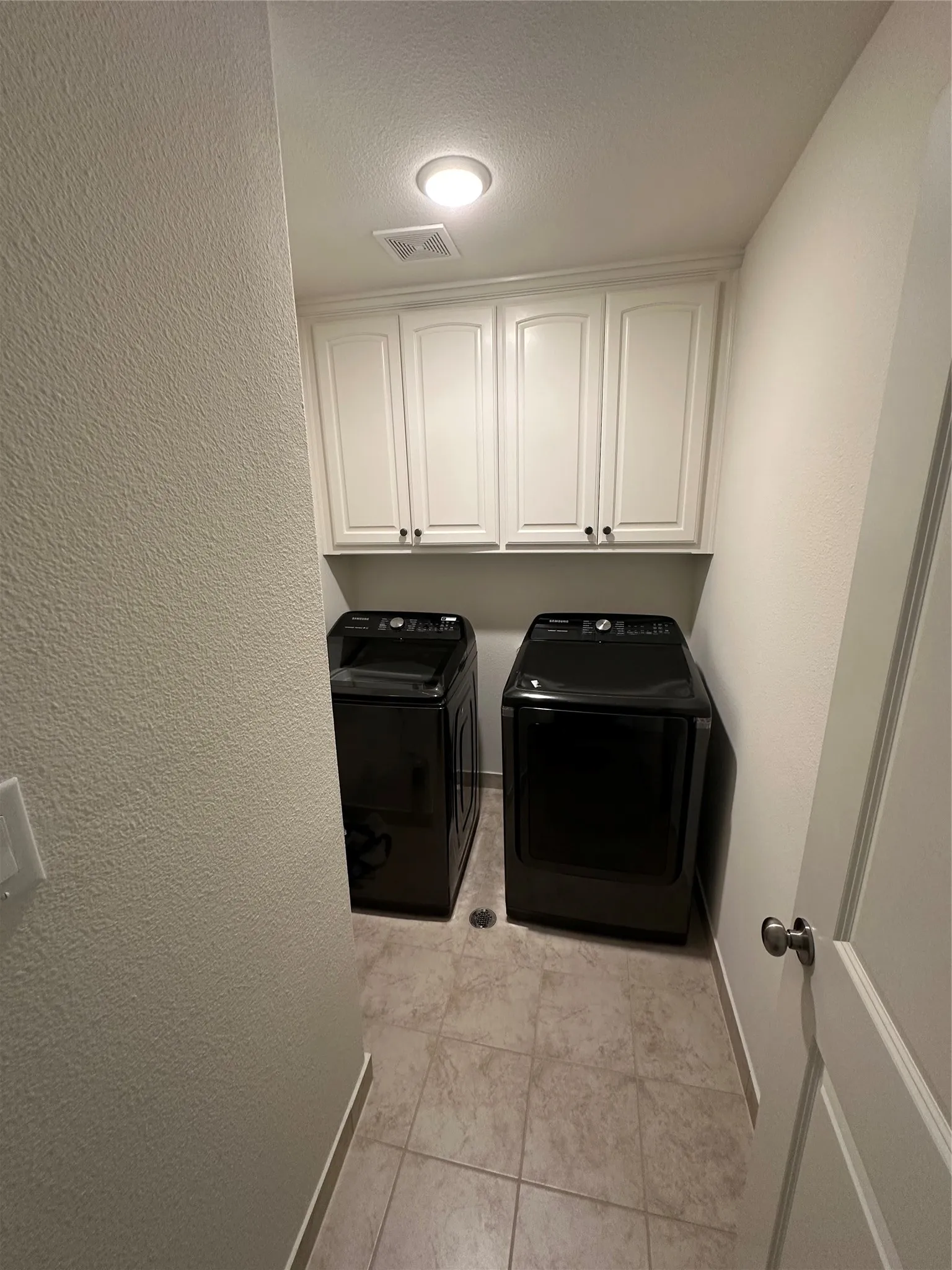 Dedicated laundry space featuring white shaker-style cabinetry, crown molding, and an integrated ceiling light