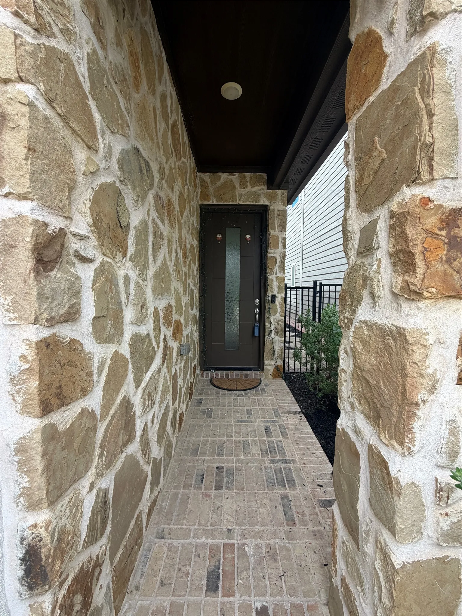 Stone veneer exterior walls defining the entryway, complemented by a paver walkway