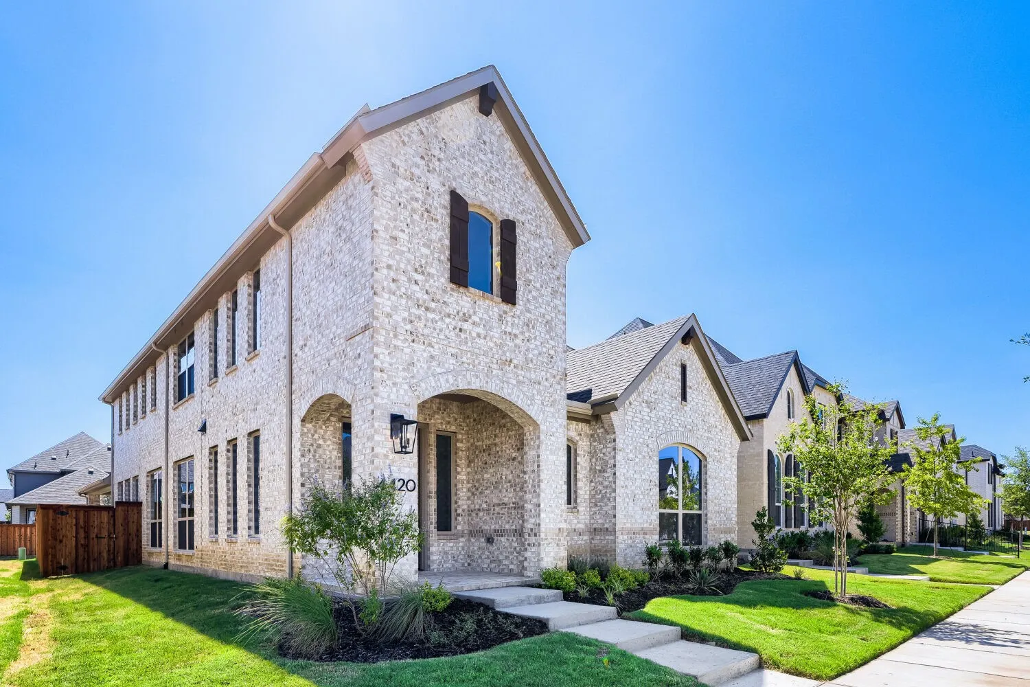 Stone-clad exterior featuring an arched entryway, dark wood shutters, and multiple gabled roofs