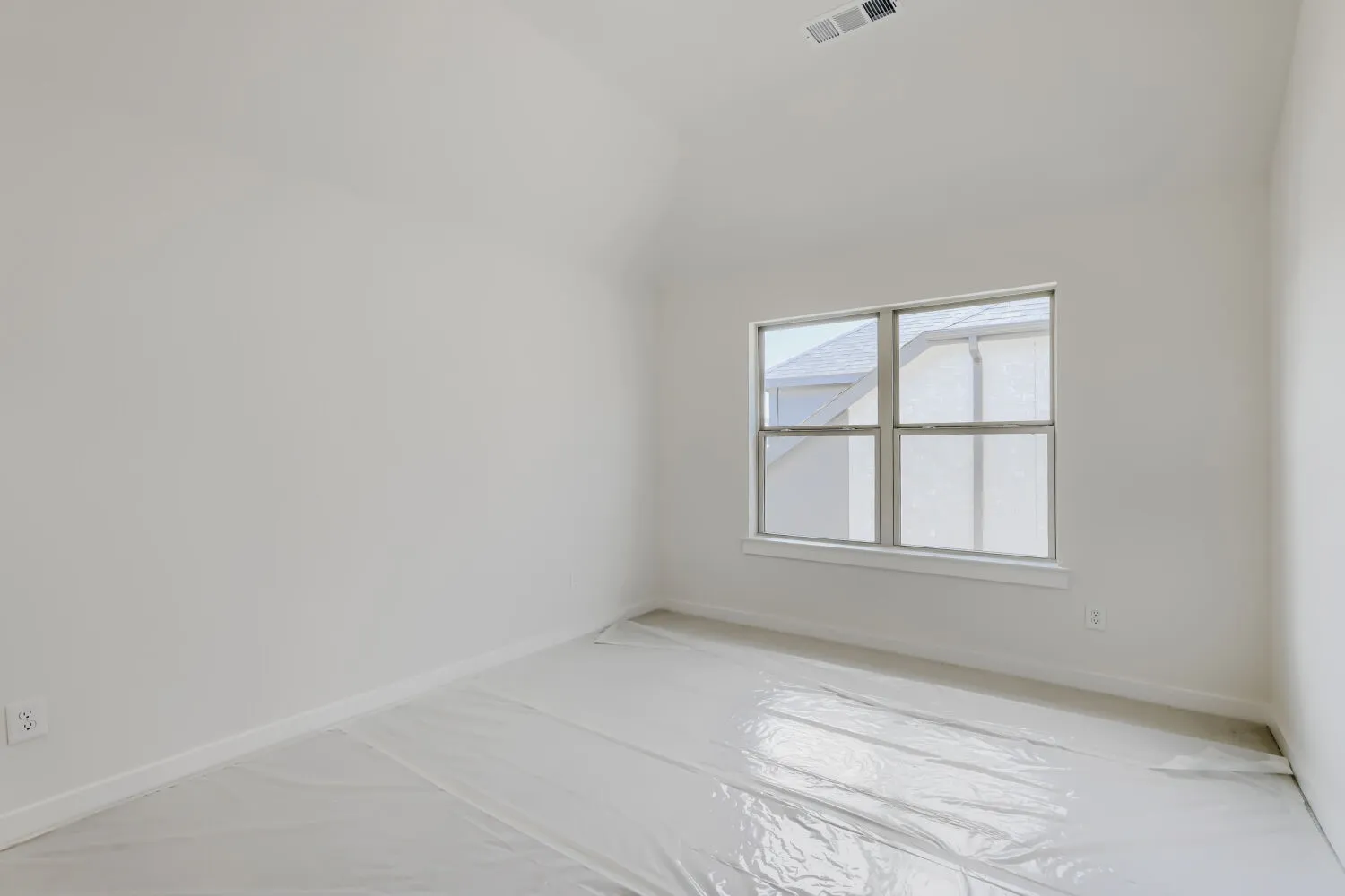 Room featuring a multi-pane window, vaulted ceiling, and neutral wall tones