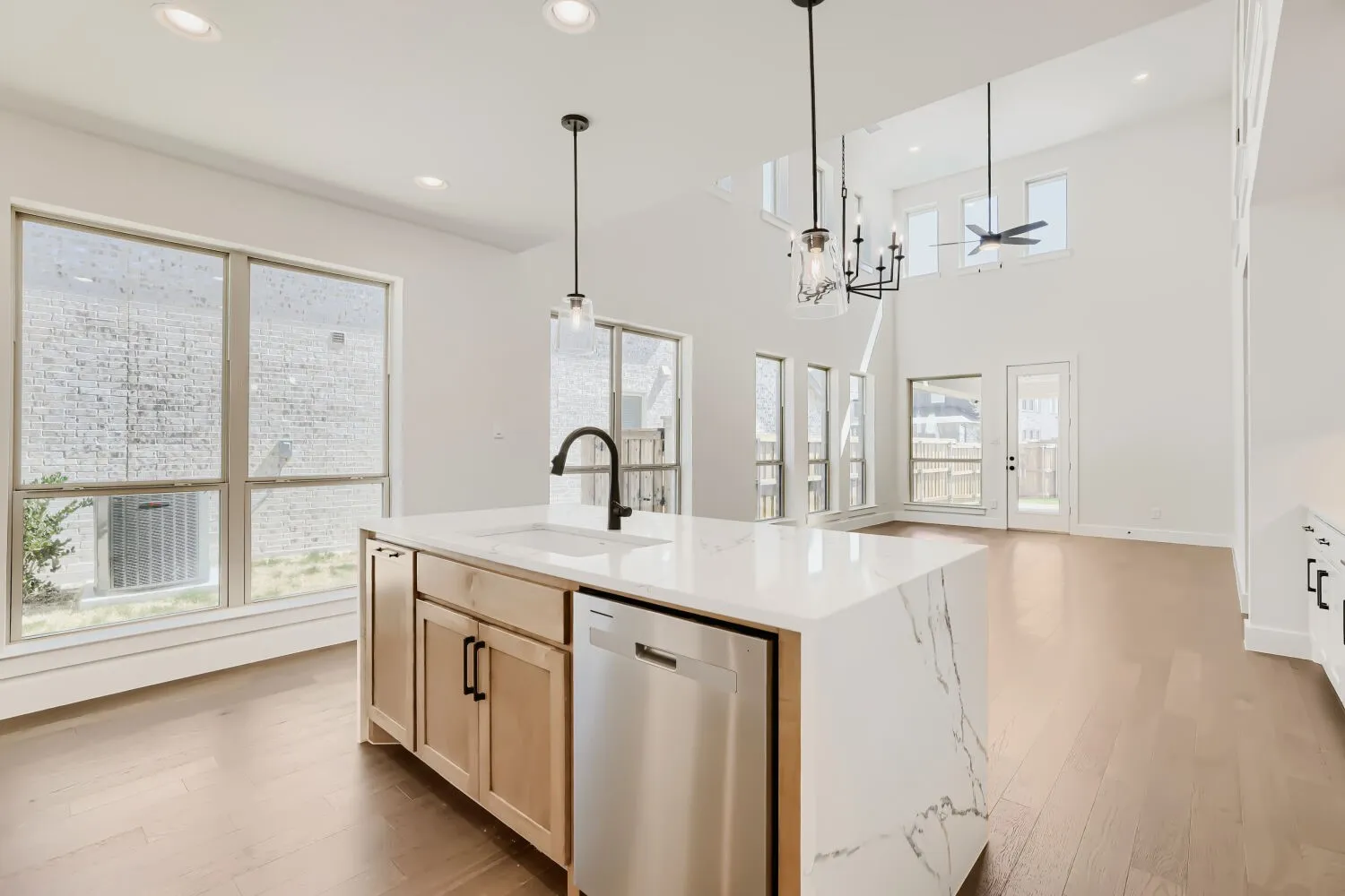 Kitchen island featuring a waterfall-edge countertop, undermount sink, and stainless steel dishwasher