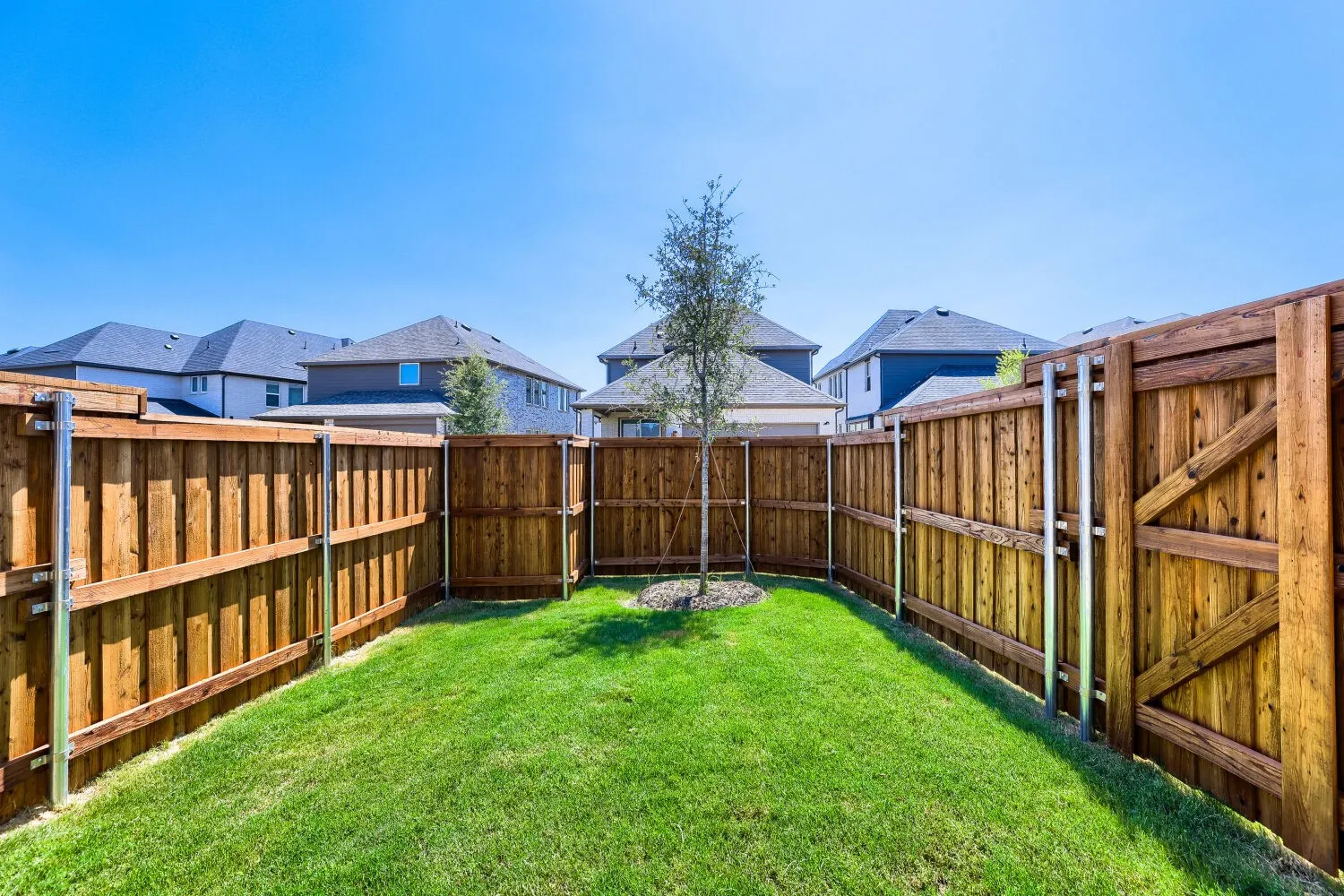 Fenced backyard featuring natural wood fencing with metal posts and a grass lawn
