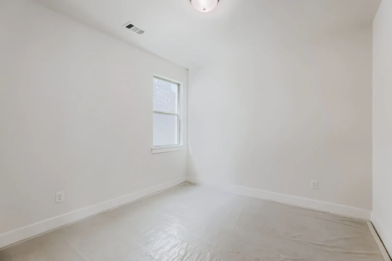 Neutral tone walls with white trim, featuring a single-pane window and overhead flush mount lighting