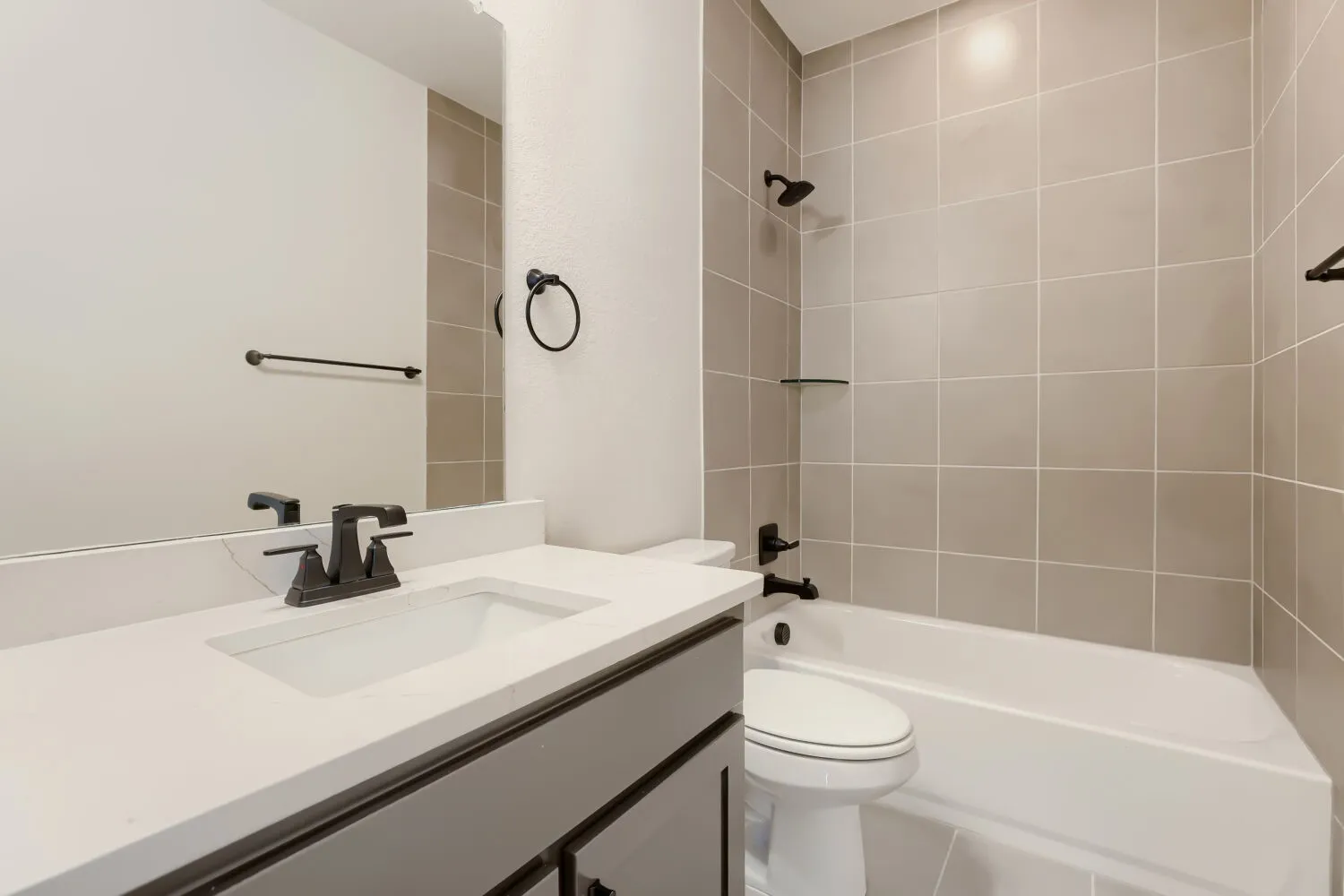 Bathroom featuring a white vanity with a rectangular undermount sink, a white countertop, and a dark bronze faucet