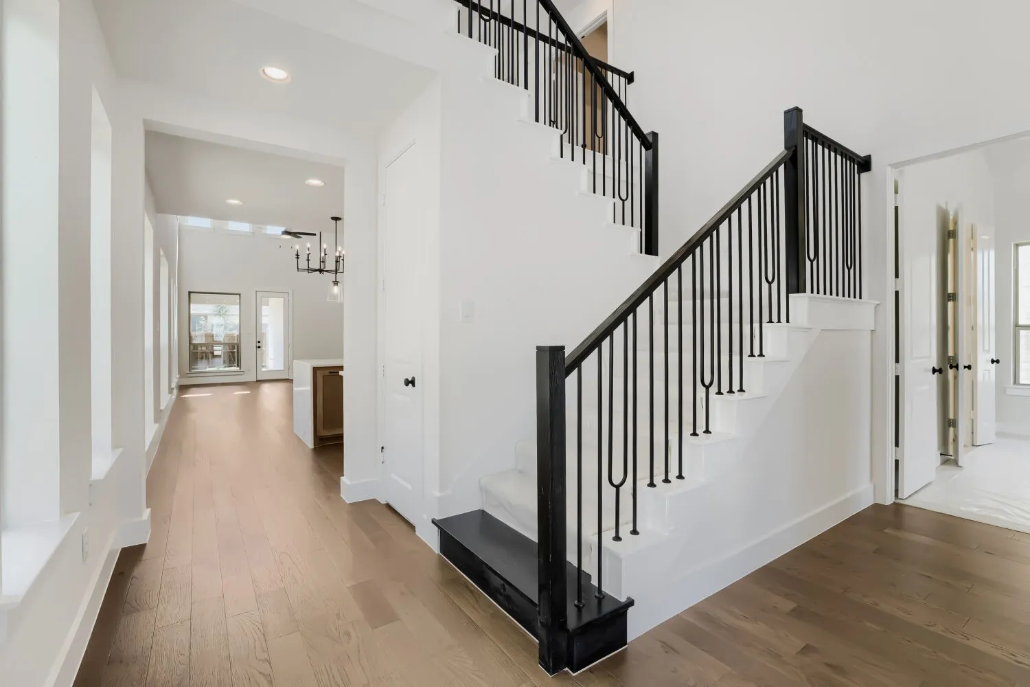 Interior entry featuring a staircase with black iron balusters, white risers, and wood-finish treads