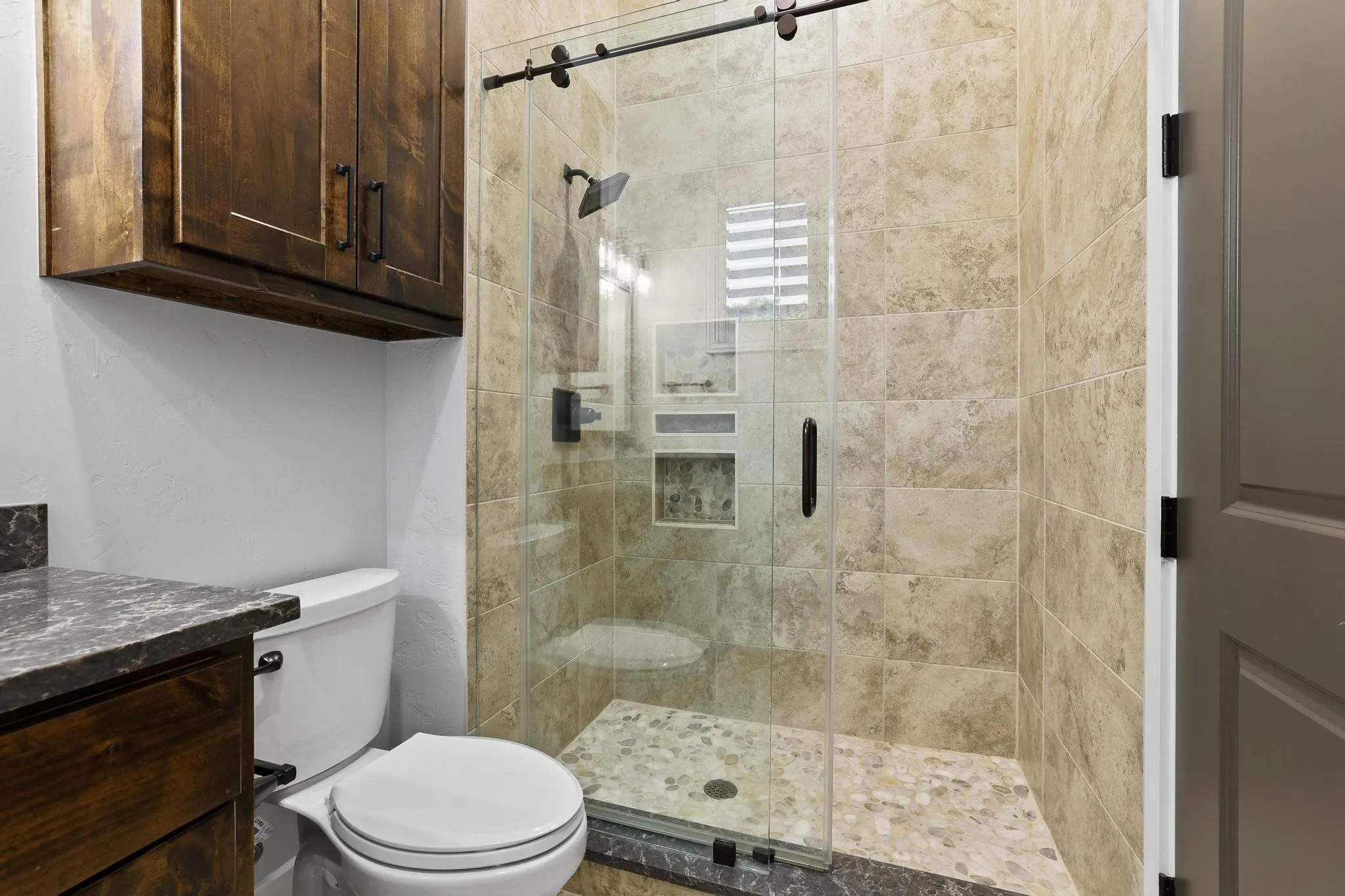 Walk-in shower with a frameless glass enclosure and an integrated tiled niche