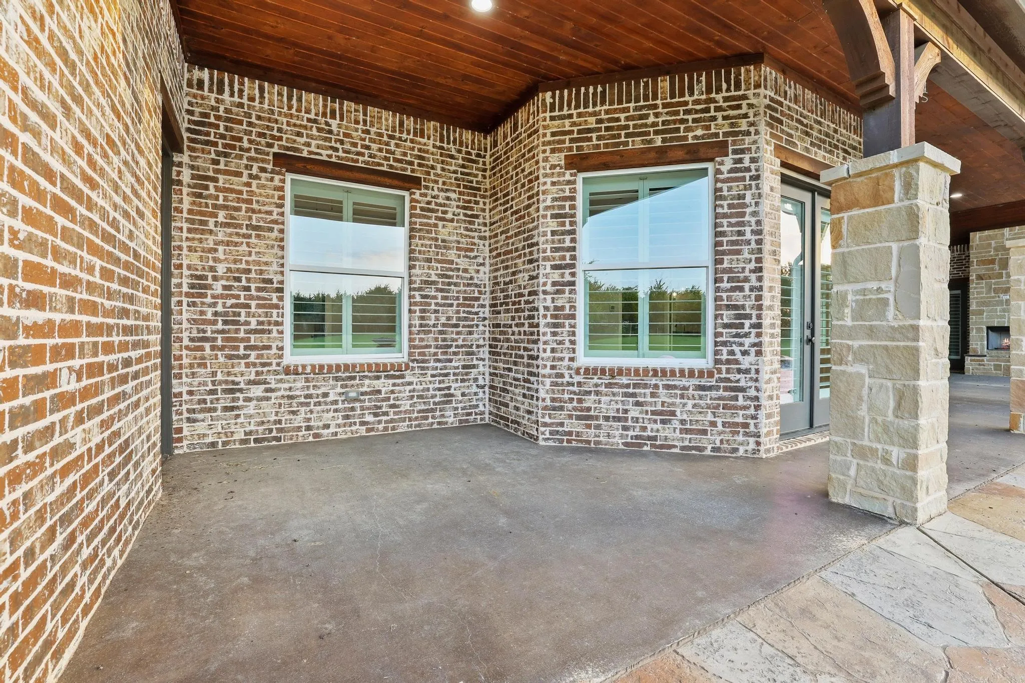 Covered concrete patio with brick and stone veneer exterior