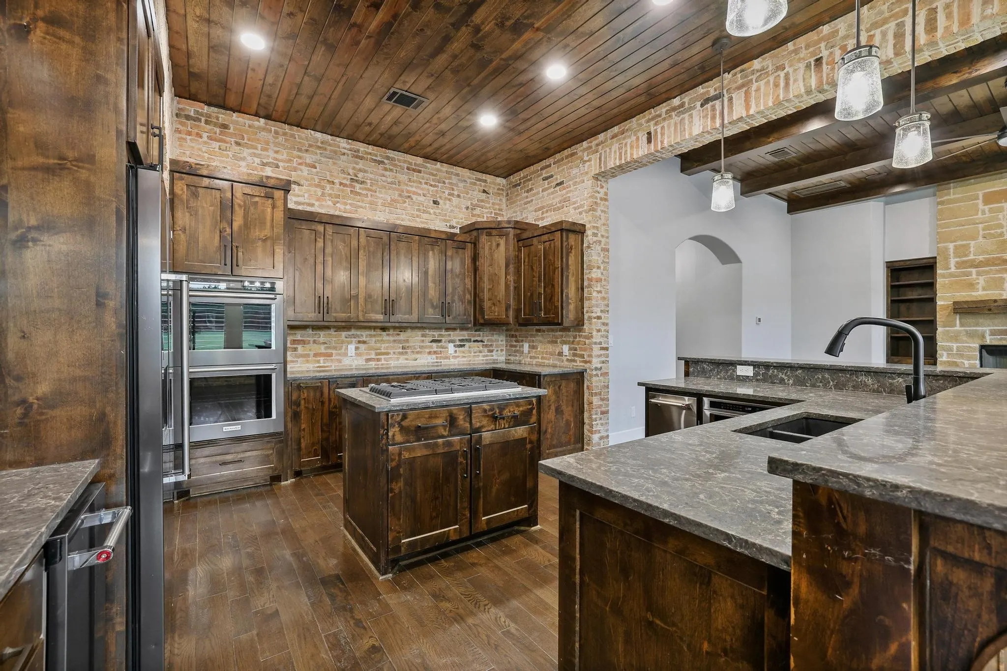 Kitchen featuring wood-finish flooring, a wood plank ceiling, and exposed brick accents