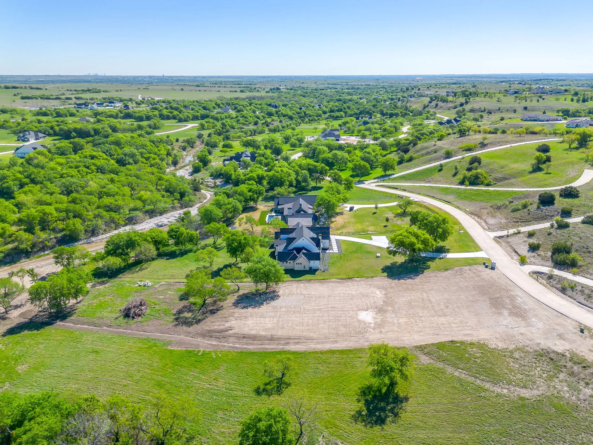 Large residential lot featuring partial clearing and a paved access road