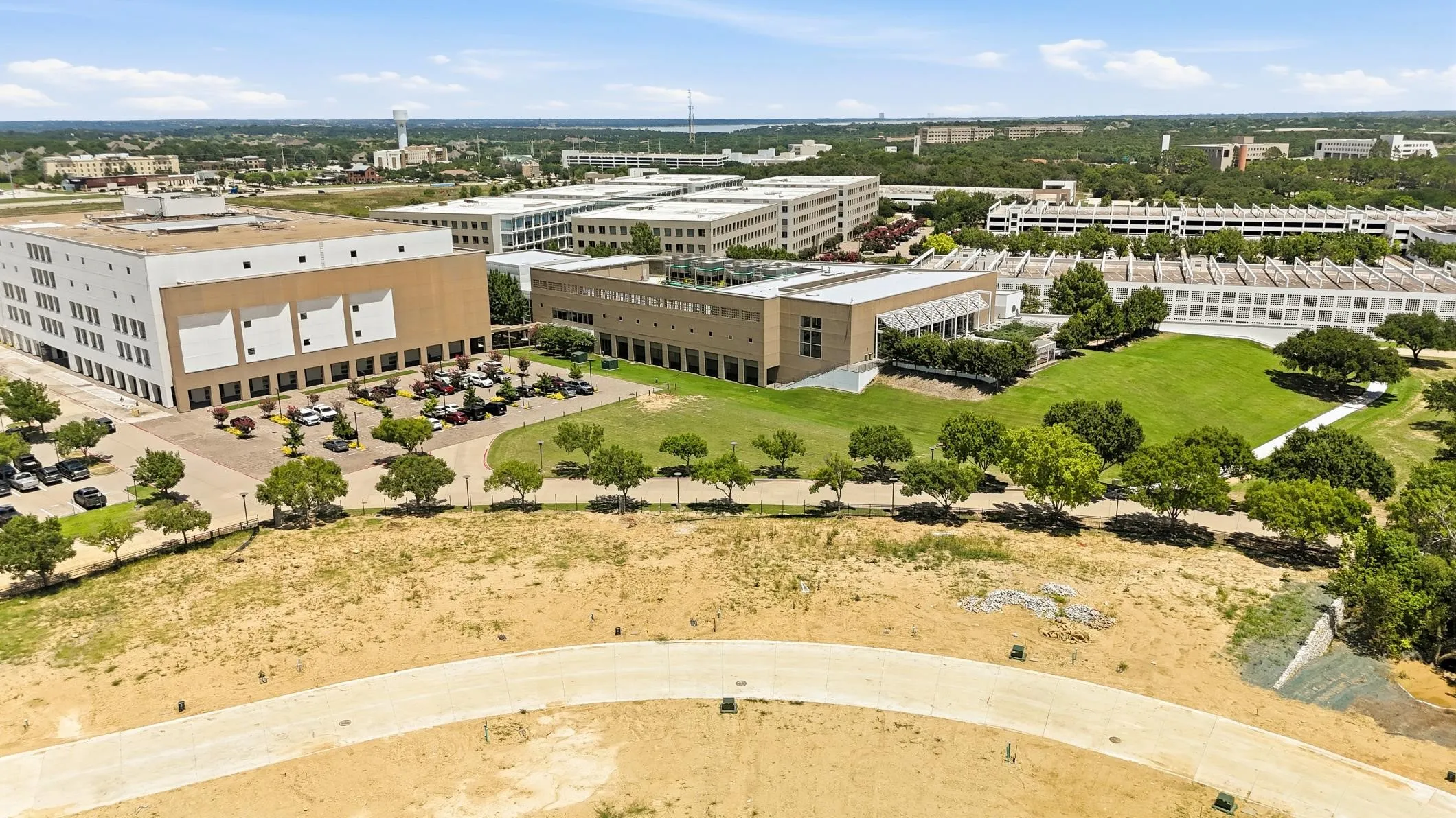 Expansive campus with multiple modern buildings, extensive parking facilities, and manicured green spaces