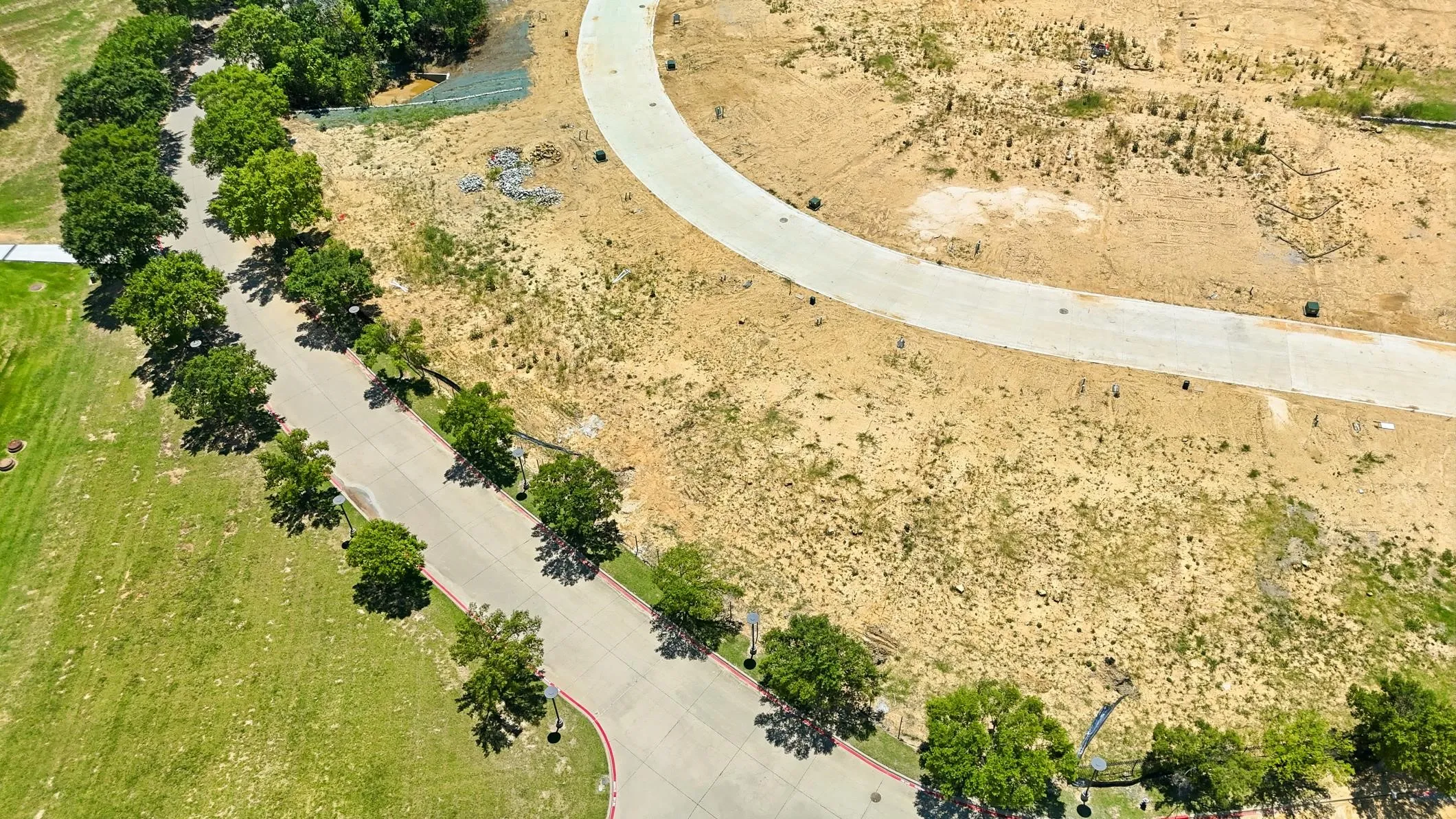 Expansive undeveloped land featuring a paved road with tree-lined street frontage