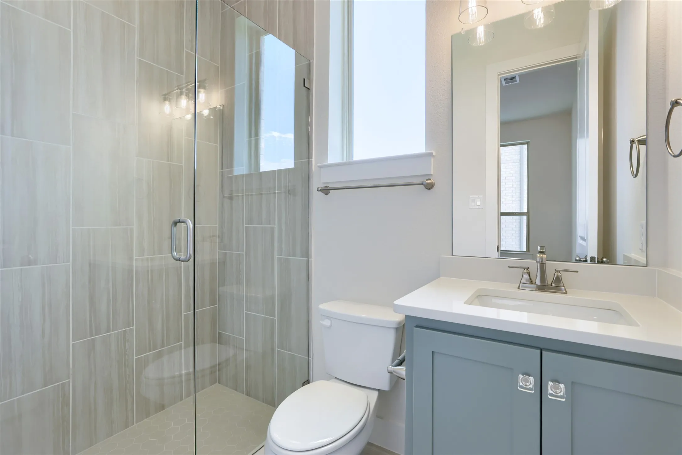 Modern bathroom featuring a glass-enclosed shower with vertical tile detailing