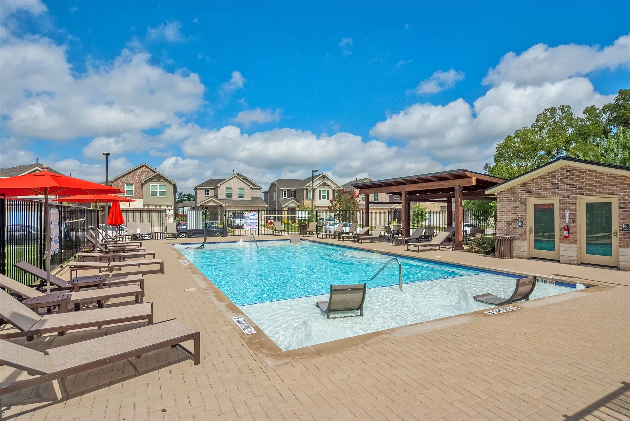 The inviting community pool area with lush greenery and relaxing lounge spots.