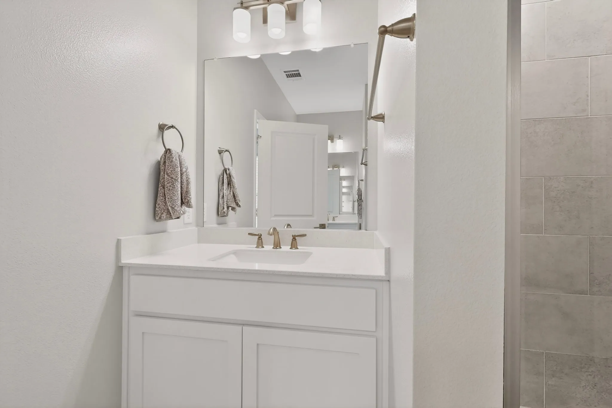 A bright primary bathroom with a vanity