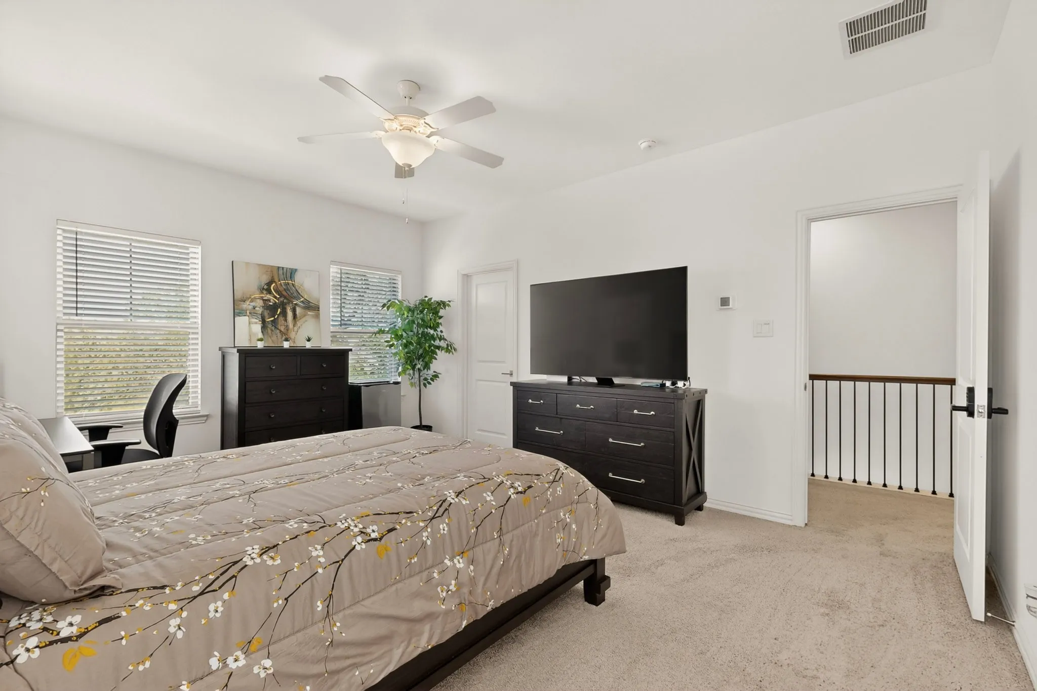 The primary bedroom with several windows and a ceiling fan, creating a refreshing and relaxing atmosphere.