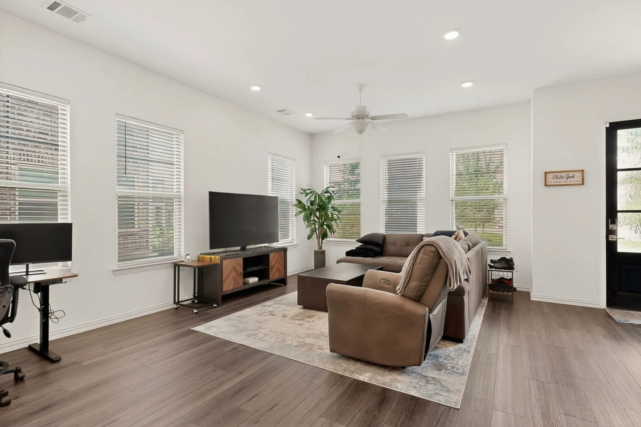 A cozy living room featuring hardwood floors, tall windows and a ceiling fan