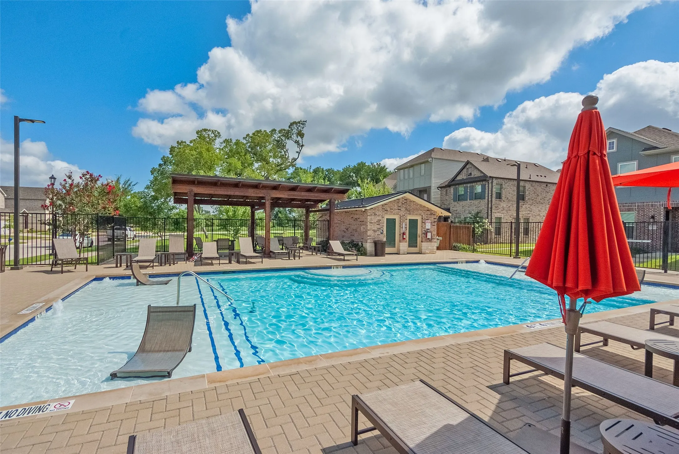 The inviting community pool area with lush greenery and relaxing lounge spots.