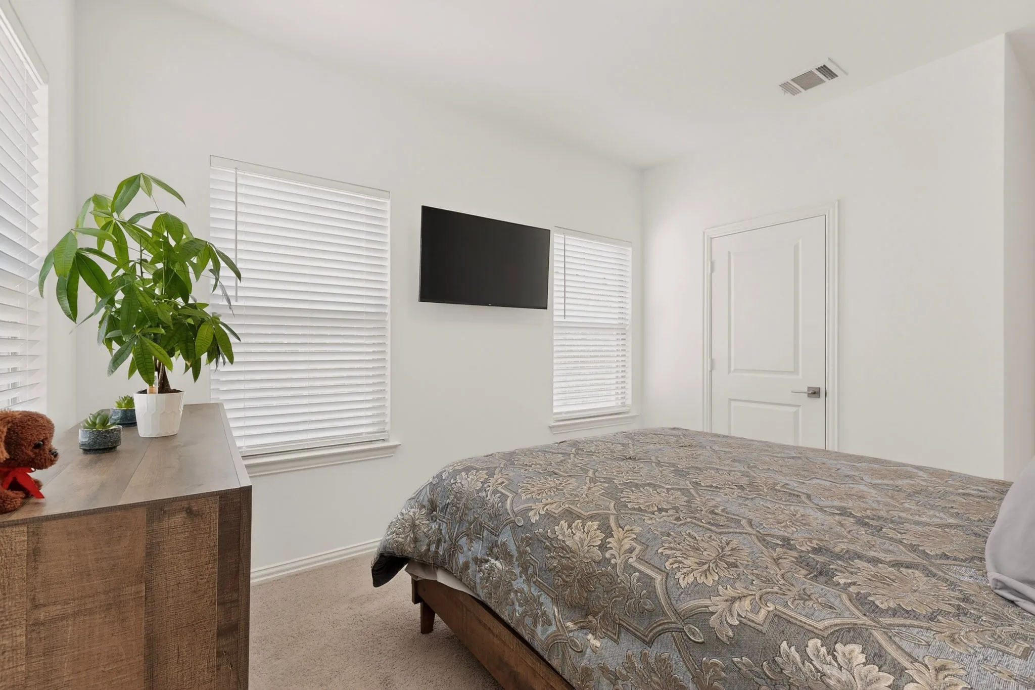 A simple, bright bedroom with several windows