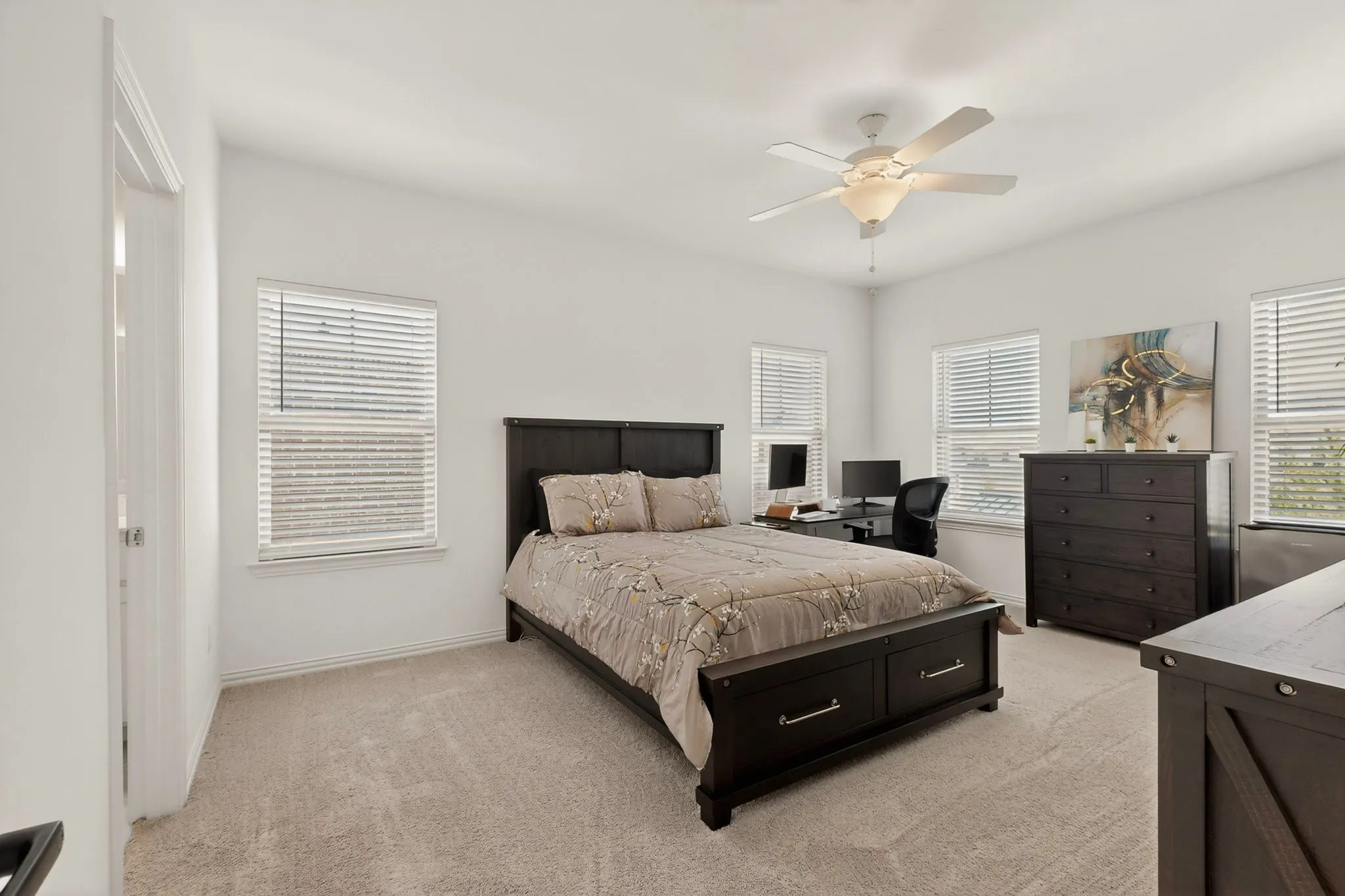 The primary bedroom with several windows and a ceiling fan, creating a refreshing and relaxing atmosphere.