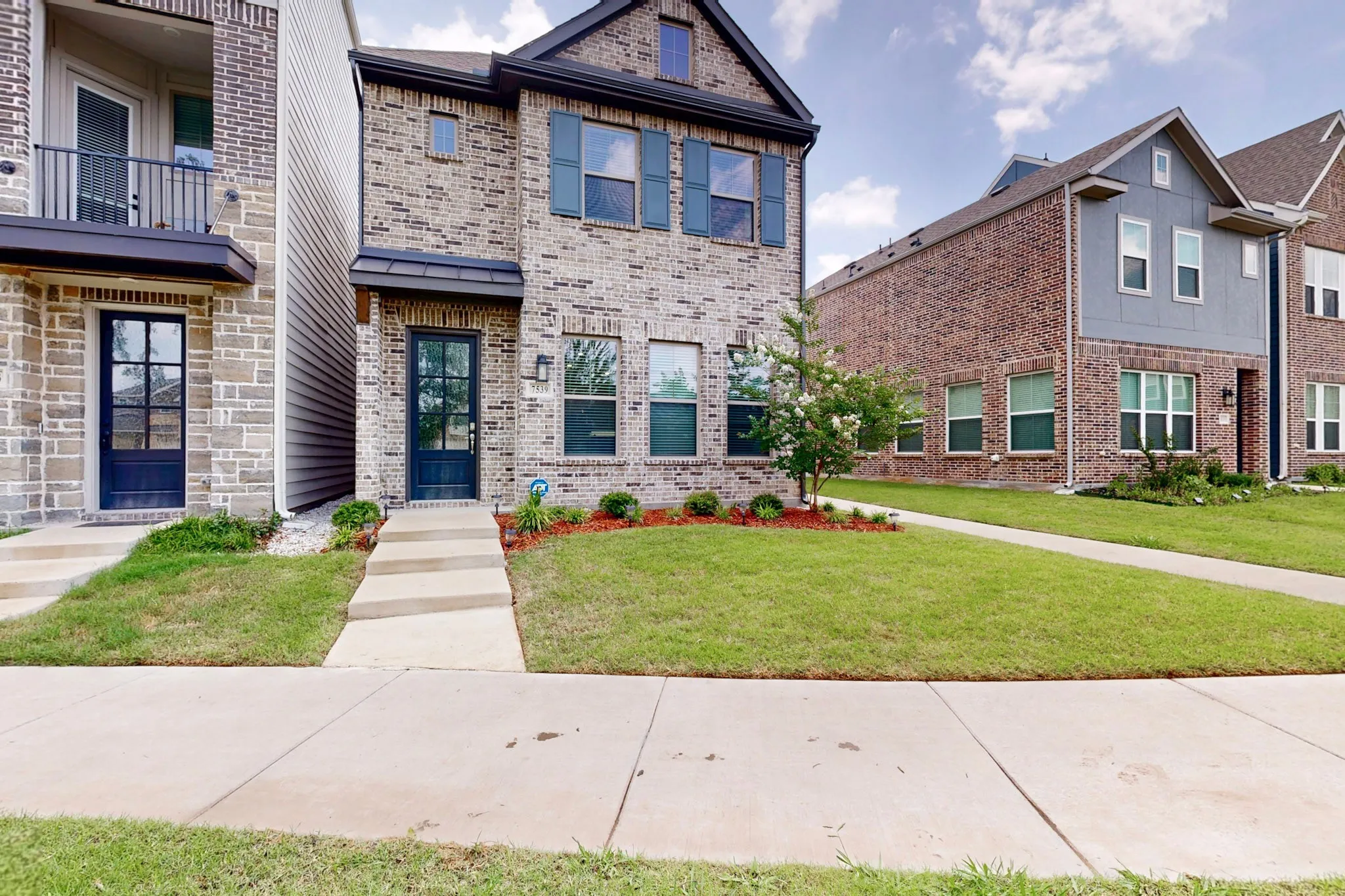Two-story brick home exterior showcasing a landscaped yard