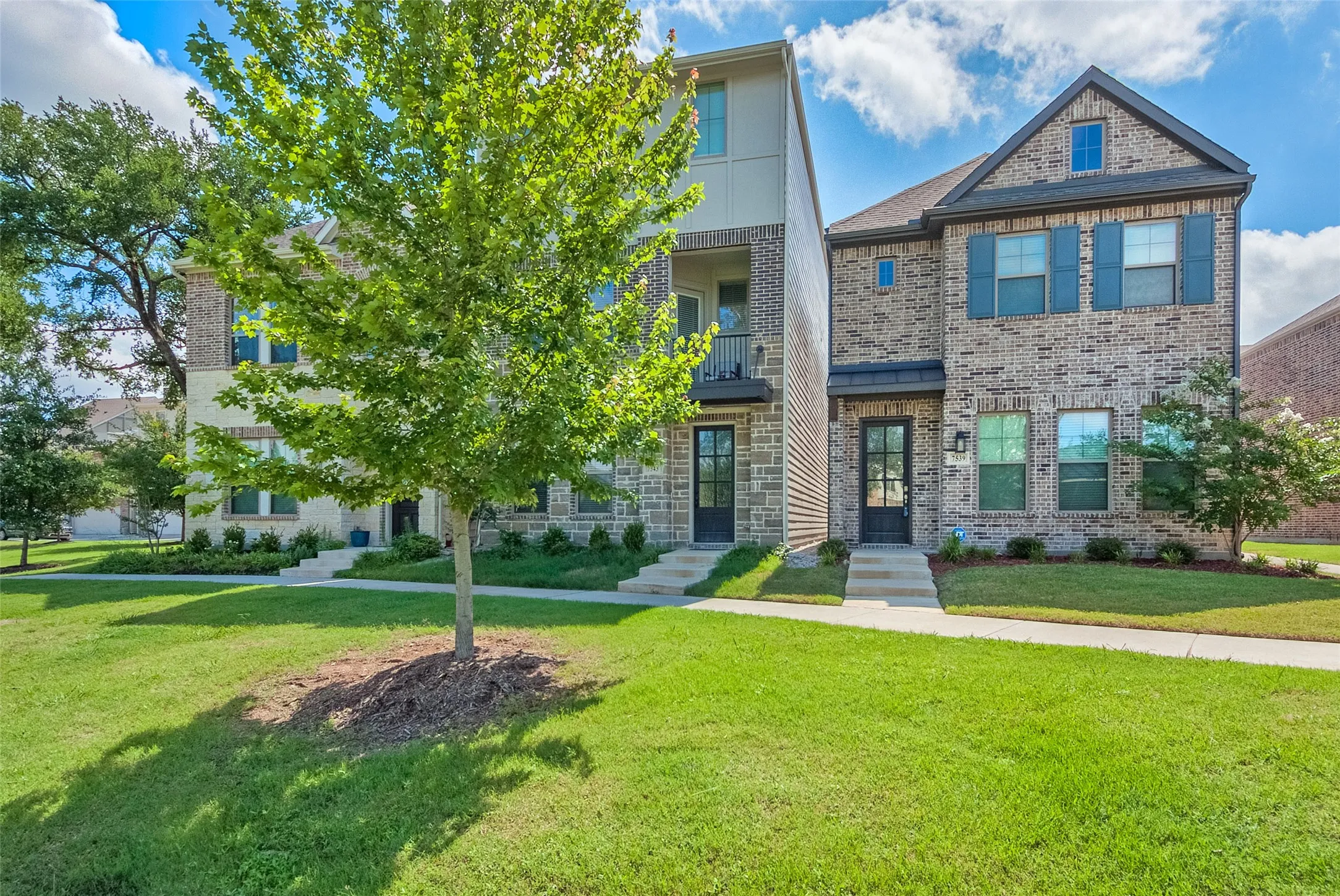 A lovely two-story house with a vibrant tree in the front yard, enhancing the home's curb appeal and charm.