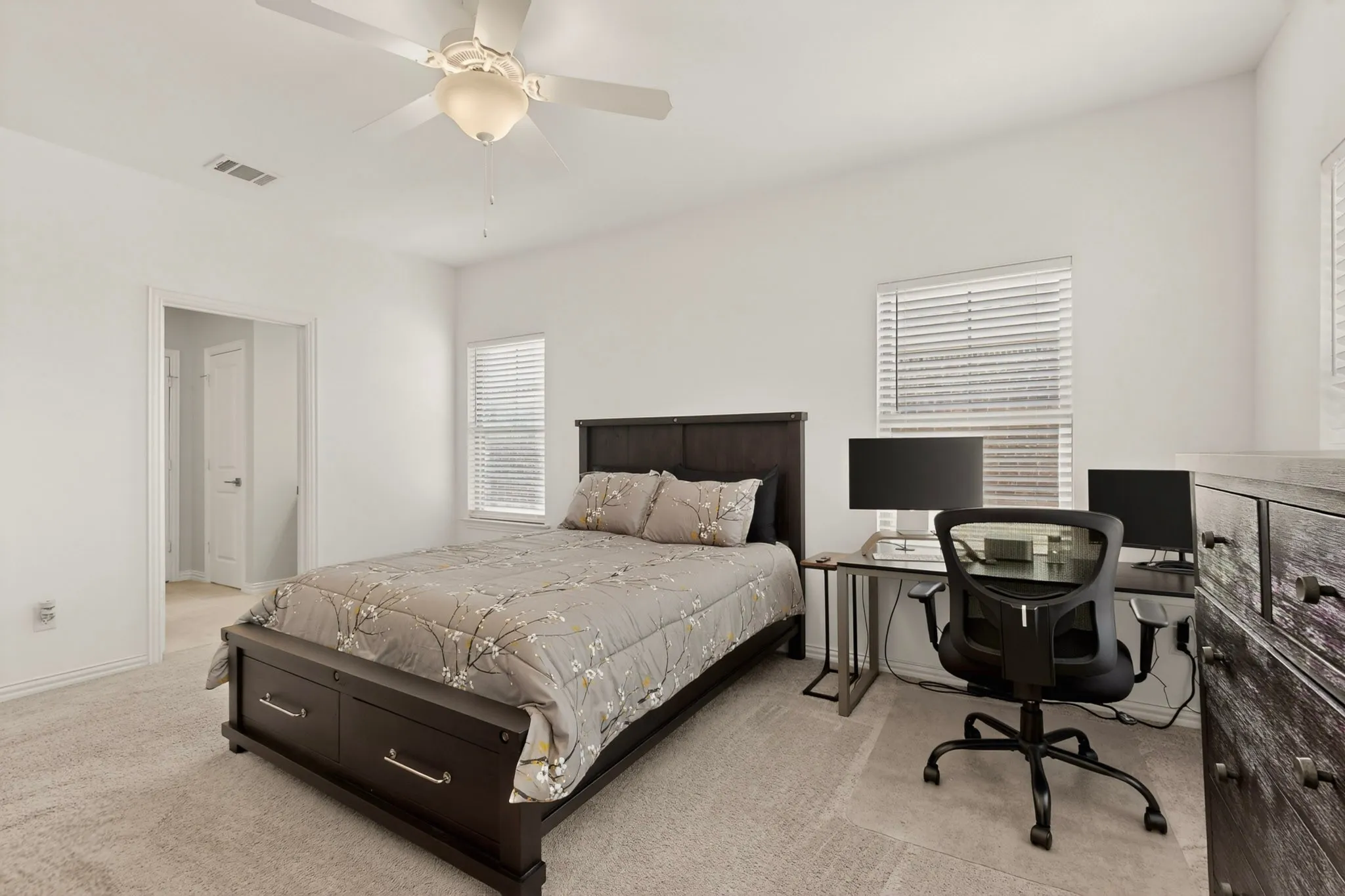 The primary bedroom with several windows and a ceiling fan, creating a refreshing and relaxing atmosphere.
