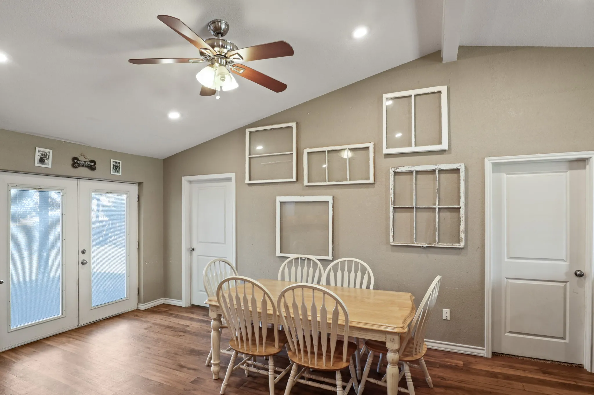 Vaulted ceiling with a ceiling fan and recessed lighting, wood-finish flooring, and white French doors