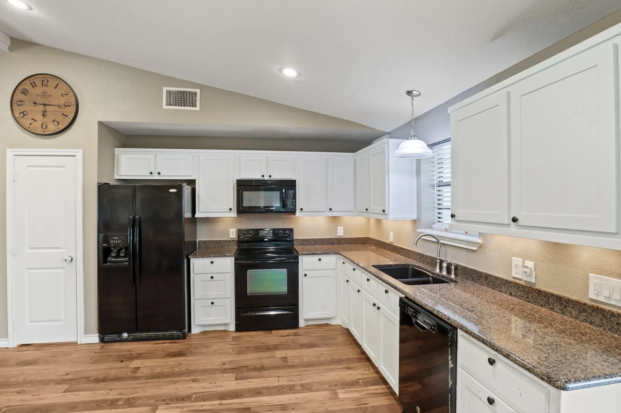 Kitchen featuring white cabinetry, dark stone countertops, wood-finish flooring, recessed lighting, and a vaulted ceiling