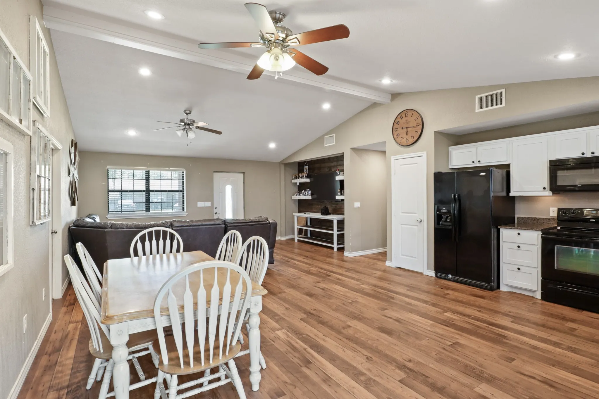 Open-concept interior featuring wood-finish flooring, vaulted ceilings, and recessed lighting