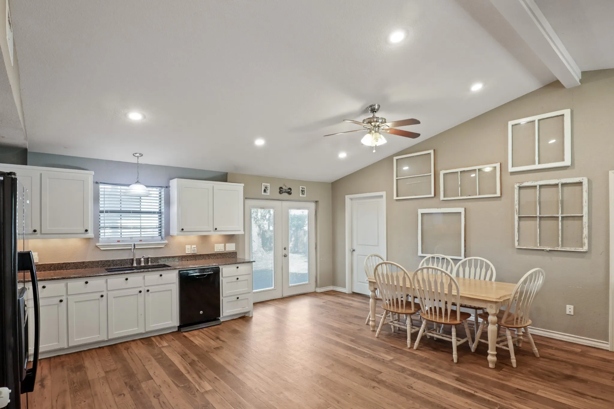 Open-concept kitchen and dining area featuring wood-finish flooring, vaulted ceilings, and recessed lighting