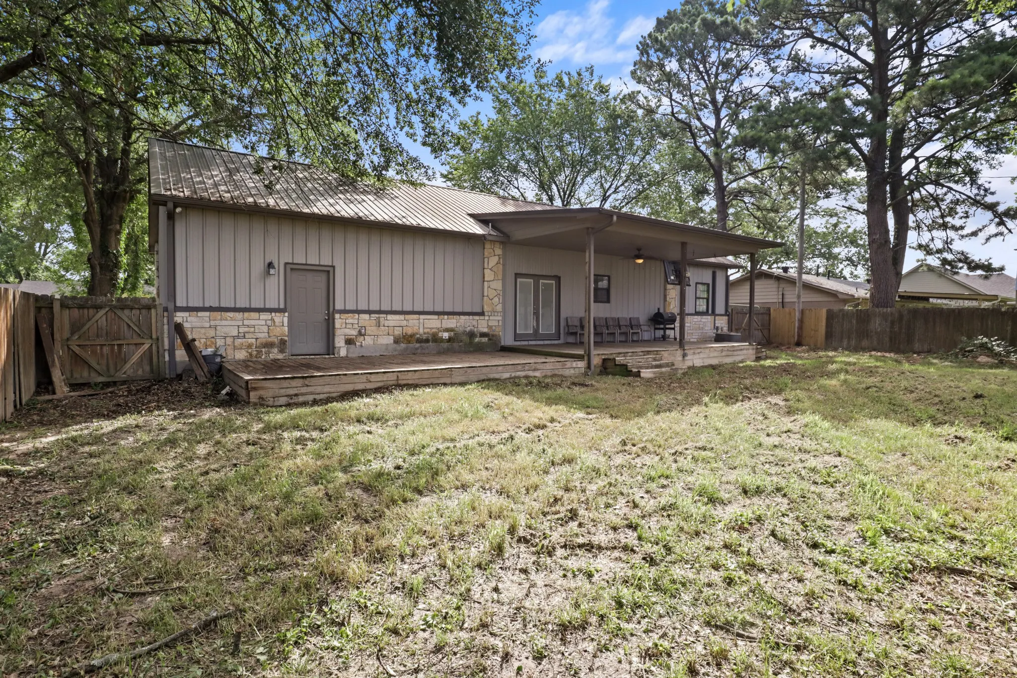 Rear exterior featuring a covered patio, double French doors, and a wood deck