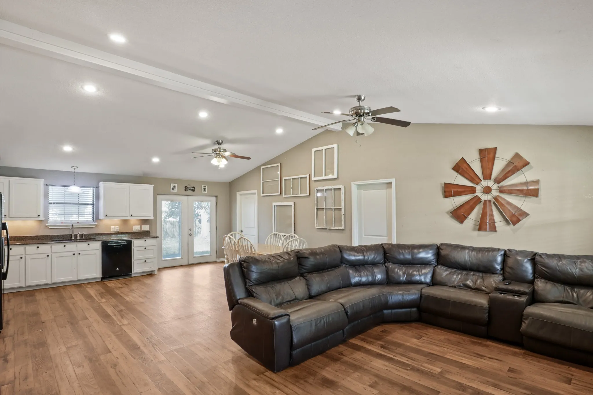 Open-concept living space featuring wood-finish flooring, vaulted ceilings with exposed beams, and recessed lighting