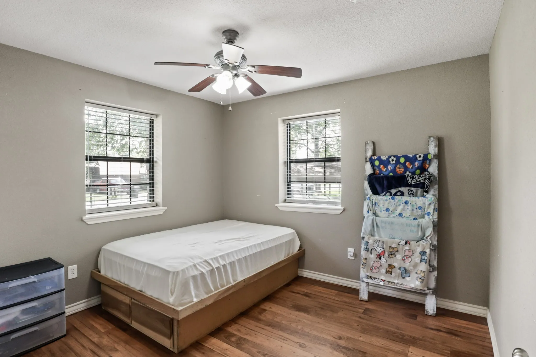 Third Bedroom featuring wood-finish flooring, two window units with blinds, a ceiling fan with integrated lighting, and neutral wall paint
