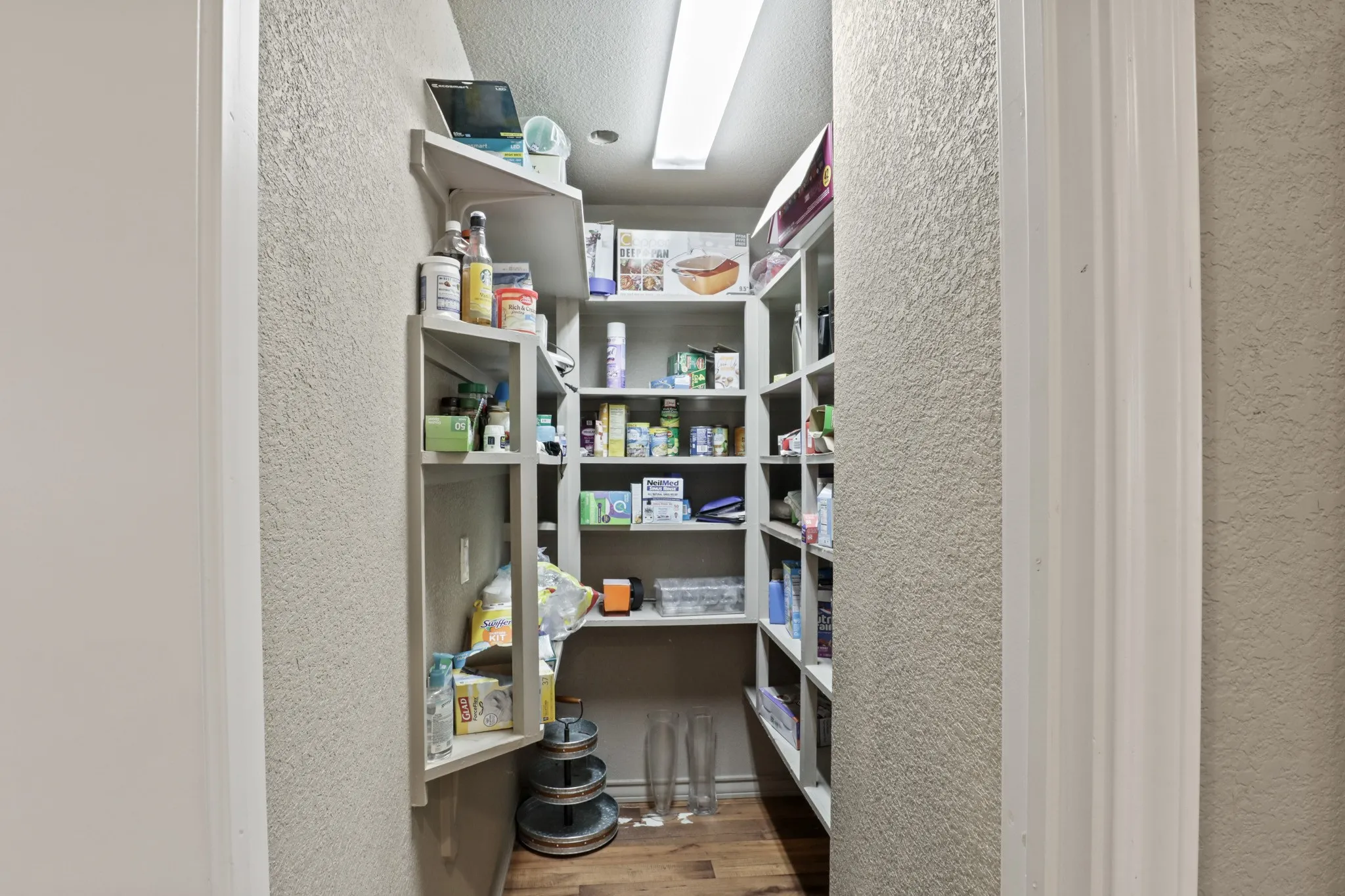 Walk-in pantry featuring expansive built-in shelving, wood-finish flooring, and recessed ceiling lighting