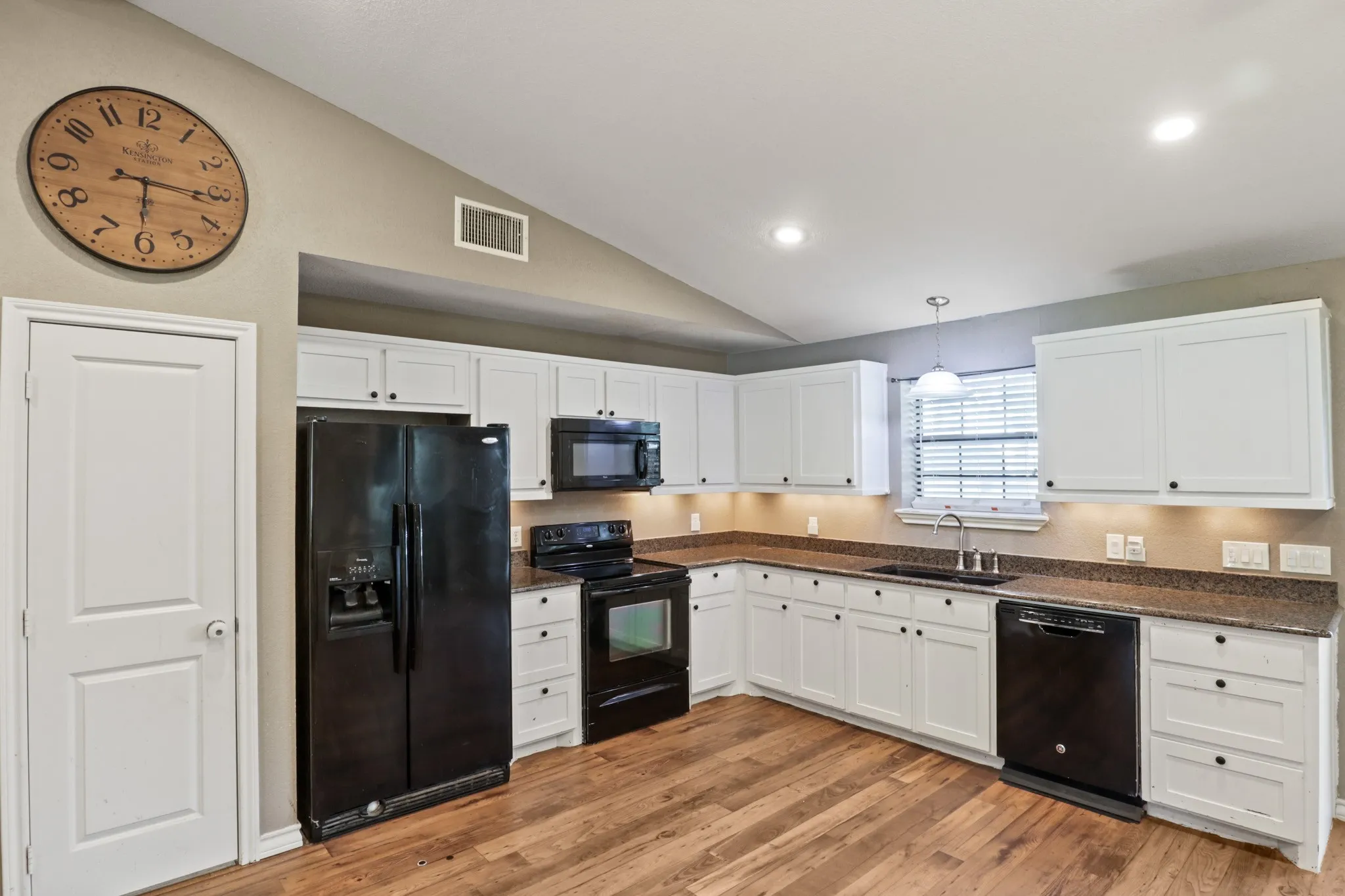 Kitchen featuring white cabinetry with dark hardware, dark countertops, and wood-finish flooring