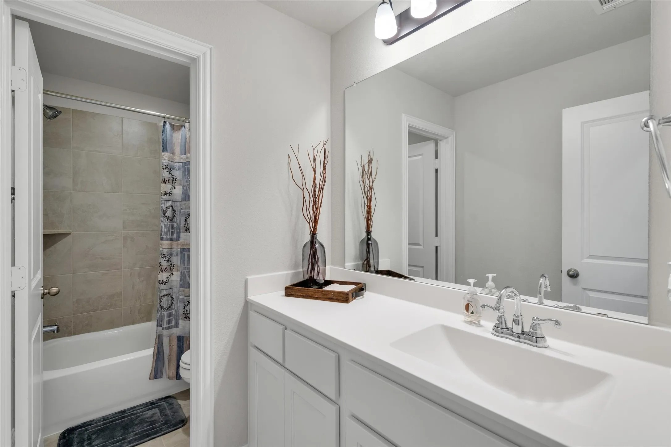 Bathroom featuring a white vanity with an integrated sink, polished chrome faucet, a large rectangular mirror, and a three-light vanity fixture